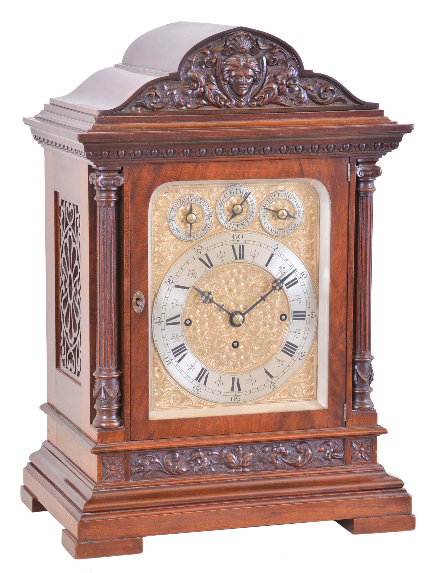 England, large bracket clock, polished mahogany architectural case, foliate carved panel above a molded, stepped base, fluted columns flanking the door, and supporting an egg and dart carved, molded cornice, the top with foliate carved paned and central mask, composite dial with gilt, engraved plate, silvered Roman numeral chapter ring with subsidiary dials for regulation and chime control, substantial three train fusee movement, and playing Whittington or Cambridge chimes at the quarters, and striking the hours on a large gong — Antique Clocks Price Guide