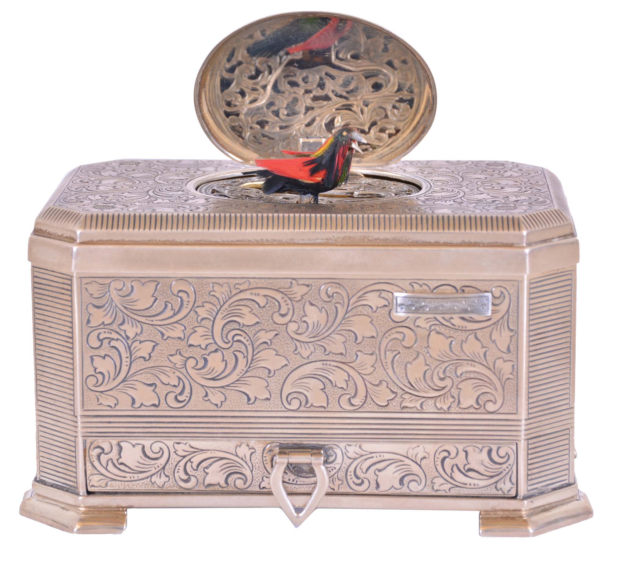 Mechanische Musikwerke Manufaktur, (MMM), Germany, singing bird box, the foliate engraved sterling silver case with canted corners, and a small drawer in the base, top with oval cover concealing a bird with brightly colored feathers, appearing and performing on demand, late 20th century — Antique Clocks Price Guide