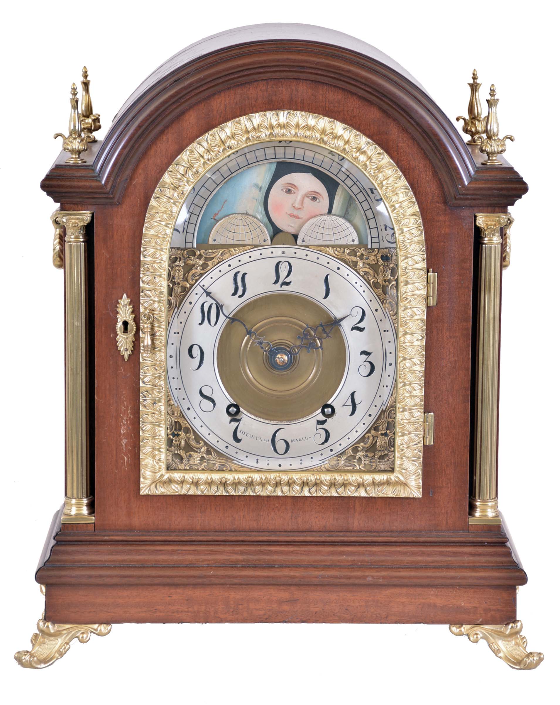 Tiffany &amp; Co. Makers, New York, large mahogany bracket clock, mahogany case with cast brass scroll feet, brass Corinthian columns flanking the arched, cast brass door with acanthus leaf decoration and thick beveled glass, each side with fabric lined brass fret and heavy cast carrying handles, the four corners of the top with brass finials, case back with mahogany door and brass screen, composite dial with gilt spandrels and moonphase diaplay in the arch, Arabic numeral silvered chapter ring marked "Tiffany &amp; Co. Makers", pierced, blued steel hands, substantial brass movement with Brocot escapement, back plate marked "Tiffany &amp; Co. Makers " and with the number 692, original pendulum, c1890 — Antique Clocks Price Guide