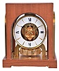 LeCoultre & Cie, Switzerland, for Gruen Guild / Cosmos Corp. "Atmos" clock, 15 jewel gilt caliber 528 movement, gilt torsion pendulum, round white painted dial with painted Roman numerals and gilt arrow markers, gilt hands with black tips, contained in a walnut veneered case with glazed, arched gilt frames
