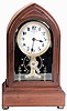 Eureka Clock Co. Ltd., London, England, battery powered mantel clock with oversized balance wheel movement in an inlayed Lancet or Beehive- style mahogany case with beveled glasses and cream porcelain dial, s#9078