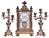 France, for Bigelow, Kennard, & Co., 3 piece mantel garniture, ornate gilt and champleve enamel crystal regulator, Arabic numeral numeral enamel dial with floral garlands, blued steel hands, and brilliant set bezel, 8 day time and strike pendule de Paris movement, gilt, brilliant set pendulum with signed portrait of a young woman, the side pieces each holding three candles, and with gilt and champleve enamel ornamented surfaces