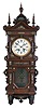 Lenzkirch, Germany, wall clock, the oak case richly ornamented with carving, moldings, and applied, cast brass elements, case top with central sphere and flanking obelisk finials, Arabic numeral silvered dial, blued steel hands, two train, 8 day quarter striking movement chiming on two gongs, fancy cast pendulum, serial #865517