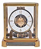 LeCoultre & Cie, Switzerland, "Atmos" clock, 15 jewel gilt caliber 528 movement, gilt torsion pendulum, round white painted dial with applied gilt Arabic numerals and arrow markers, gilt hands, all contained in a glazed rectangular case with removable top, presentation plaque mounted to front of base, with Atmos pamphlet, serial #123665