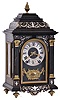 France, for W. Johnson & Son, London, miniature bracket clock, ebonized case with contrasting leaf, vine, and bellflower inlay, front with inlaid pilasters flanking the arched glass, Roman numeral silvered dial with fancy gilt hands, above a gilt ornament with central cartouche, all on a black moire ground, 8 day time and strike movement with square plates