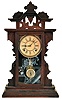 Clocks- 3 (Three): (1) Waterbury Clock Co., Waterbury, Conn., "Foster" shelf clock with an 8 day spring driven time and strike movement in a walnut case, c1900. (2) "Regal No. ?" Gilbert Kitchen Mantel clock with an 8 day spring driven time and strike movement in an oak case, c1900. (3) E. N. Welch Clock Co., Forestville, Conn., "Coghlan" shelf clock with an 8 day spring driven time and strike movement in a walnut case, c1886.