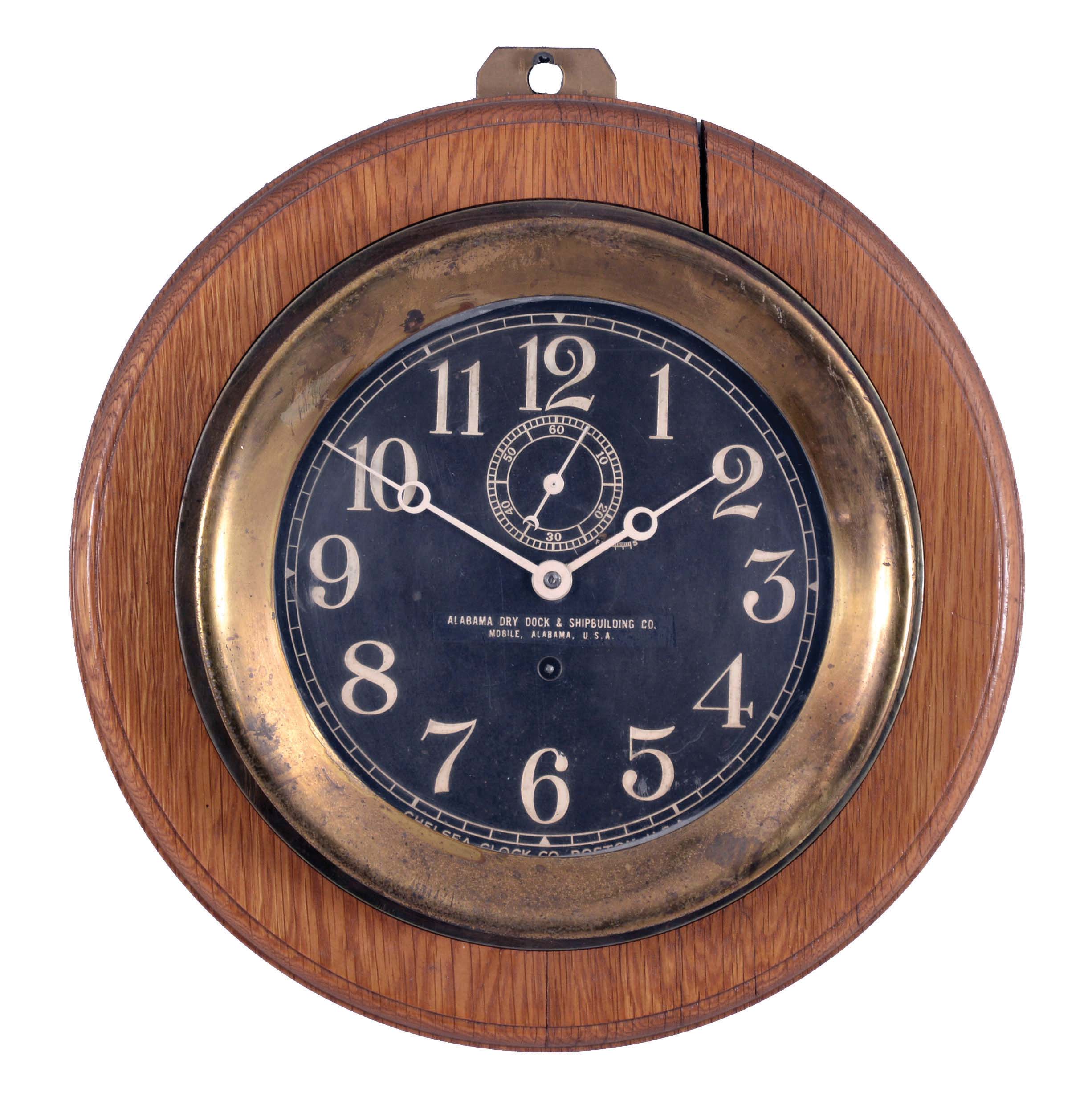 Chelsea Clock Co., Boston, Mass., for the Alabama Dry Dock and Shipbuilding Co., Mobile, Alabama, 8 1/2" "Pilot House" clock, polished brass case with mounting flange, fixed to round oak board with hanger, black dial with white Arabic numerals and hands, 8 day timepiece movement with rectangular plates, serial #300486 — Antique Clocks Price Guide