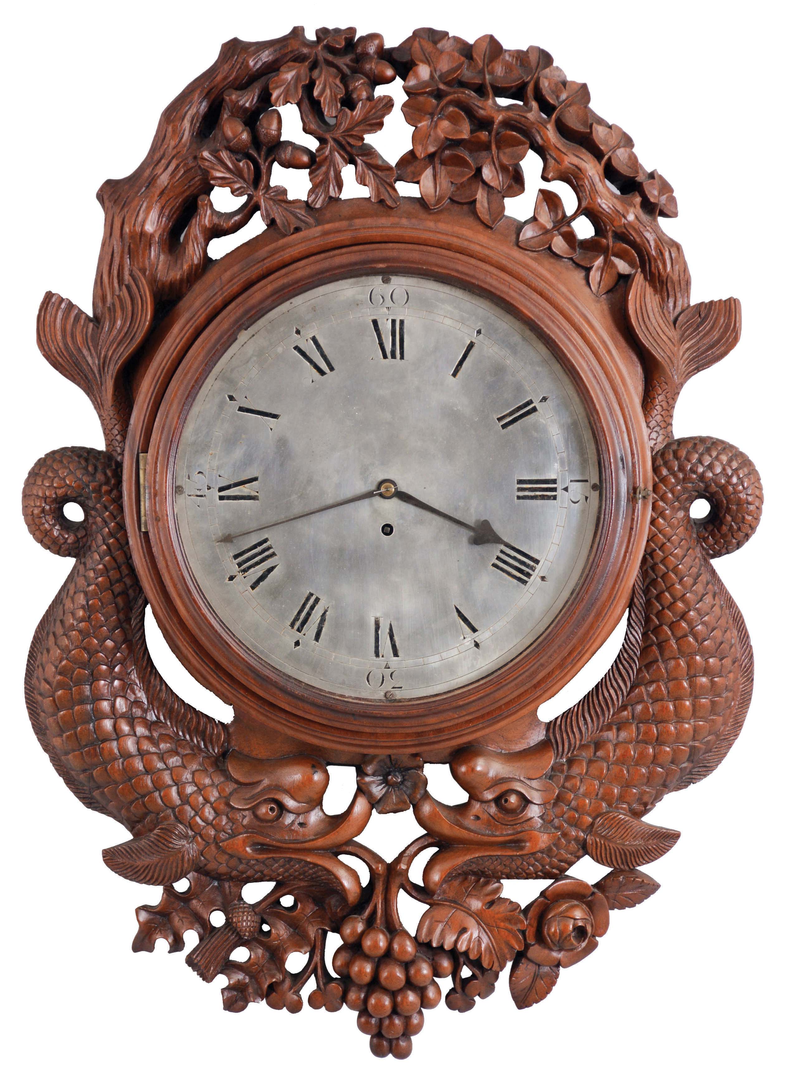 England, an ornately carved gallery timepiece, the mahogany case with turned bezel, surrounded with carved, foliate ornament, and with a pair of full bodied, facing dolphins below, Roman numeral silvered dial, 8 day, fusee timepiece movement — Antique Clocks Price Guide