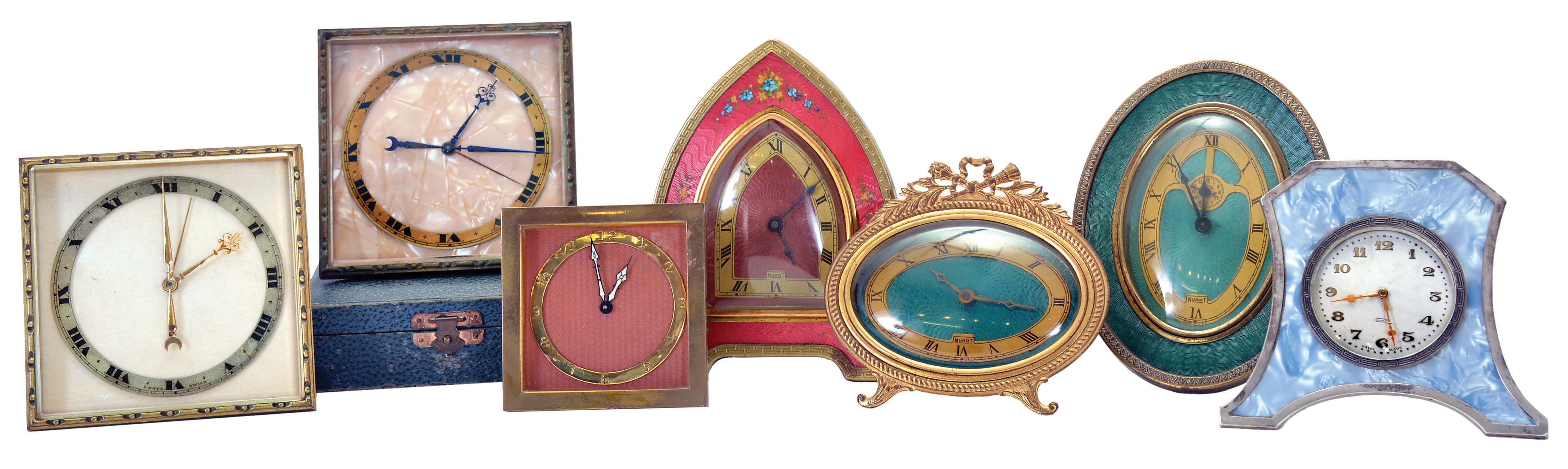 Clocks- 7 (Seven): Two square, easel back Swiss desk clocks, 8 day time and alarm, one with outer case, three "Nuart" desk clocks with faux guilloche enamel, two with easel backs, one with alarm, all 30 hour, a smaller, square Swiss, 8 day, also with easel back, and a Deco style Swiss with silver trimmed case and 8 day movement — Antique Clocks Price Guide