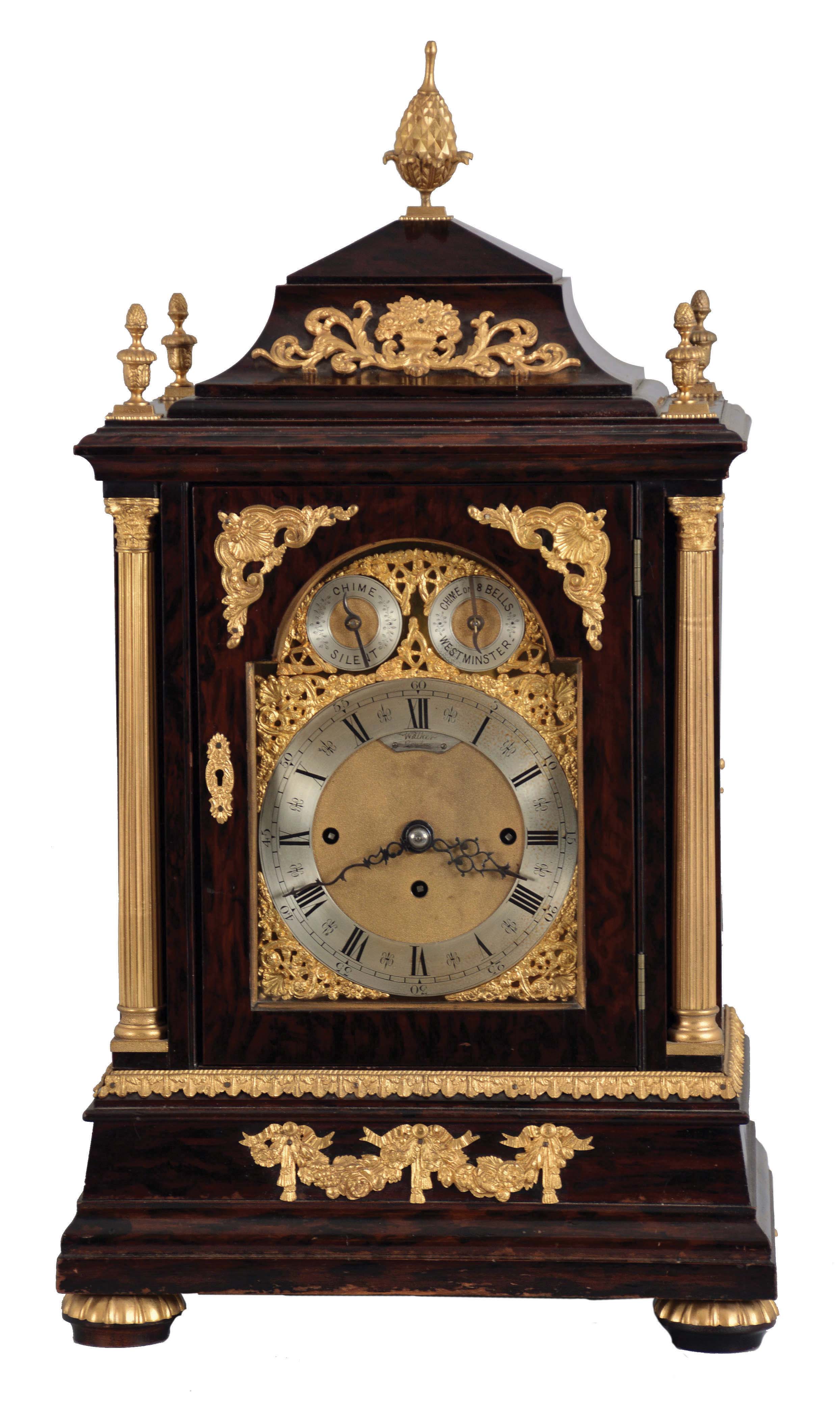 Walker, London, a large, three train bracket clock chiming on eight bells, mahogany case with faux rosewood finish and turned, gilt gadroon mounted feet, the base with gilt, floral festoons, door with gilt mounts, front corners with flanking, reeded columns supporting the molded cornice and caddy top, also with gilt foliate ornament, and pineapple finial, case sides with cast, pierced frets decorated with rococo motifs and central masks, composite dial with matted center, Roman numeral, silvered chapter ring below subsidiary chime selection dials, pierced, blued steel hands, and substantial, three train fusee movement — Antique Clocks Price Guide