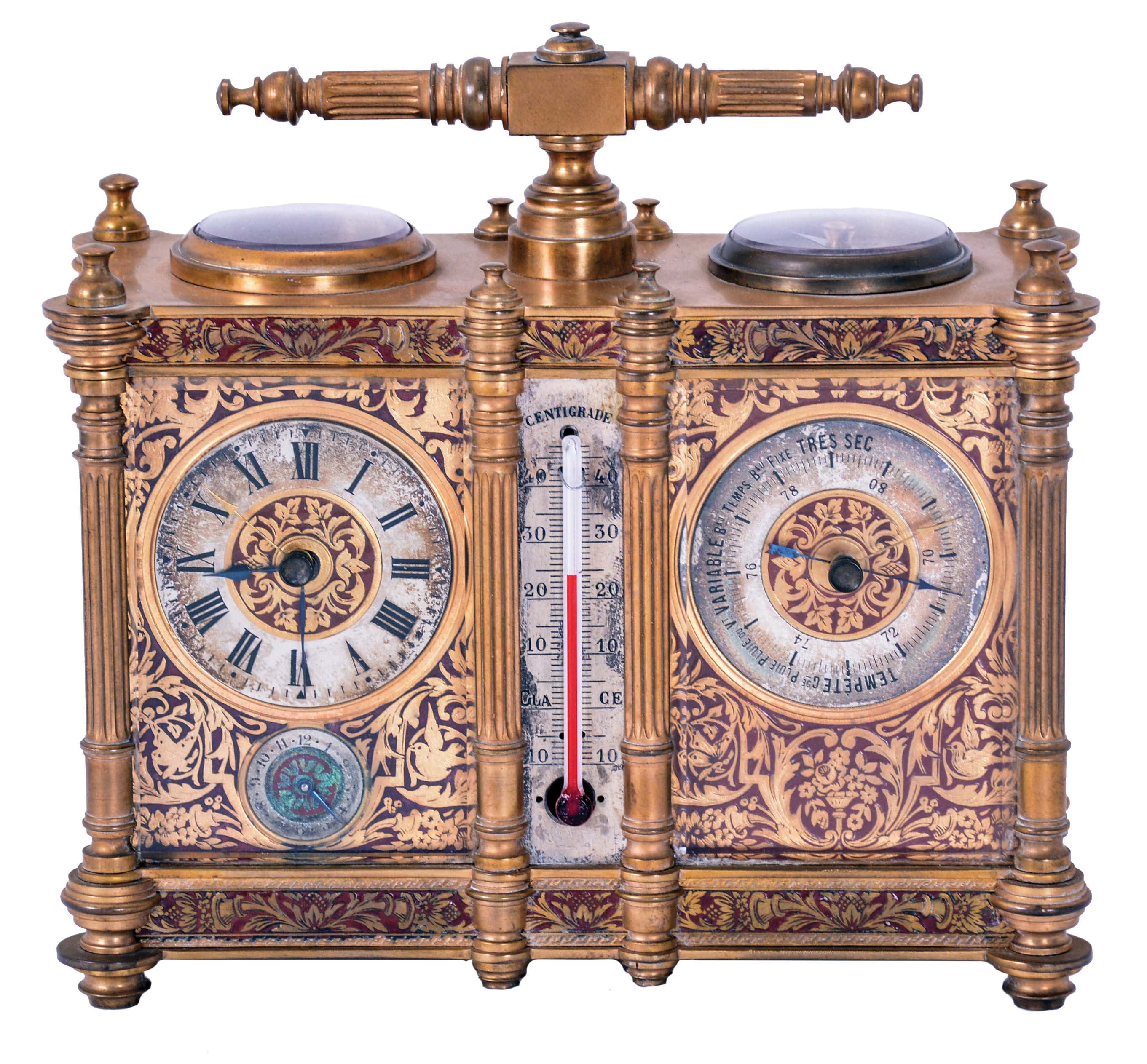 Victorian desk compendium of double carriage clock form, gilt brass case with turned feet, finials, and fluted columns, eight beveled glasses, and engraved panels with red enamel infill, the left side containing the clock, Roman numeral silvered dial, blued steel hands, 8 day time and alarm movement with lever platform, the right side with barometer and compass, both with silvered dials and blued steel indicators, case front also mounted with centigrade thermometer, case top with carrying handle — Antique Clocks Price Guide