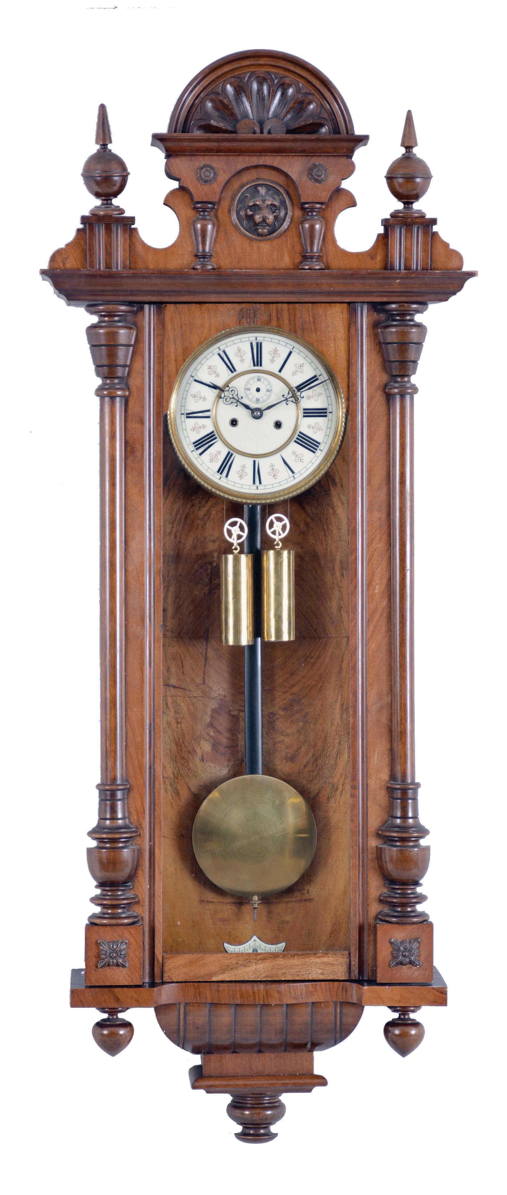 Clocks- 2 (Two): Both Vienna regulators, the first with walnut case and ebonized accents, incurved bottom bracket with gadroon, door with nicely carved half columns and bevelled glass, frieze with applied carving below a projecting cornice, and with carved crest, Roman numeral white enamel dial, pierced hands, and 8 day, weight driven time and strike movement, the other with walnut veneered case, ribbed bottom bracket, door with applied half columns, and two part crest with carved and turned ornament, Roman numeral white enamel dial, pierced hands, and 8 day, weight driven, time and strike movement — Antique Clocks Price Guide