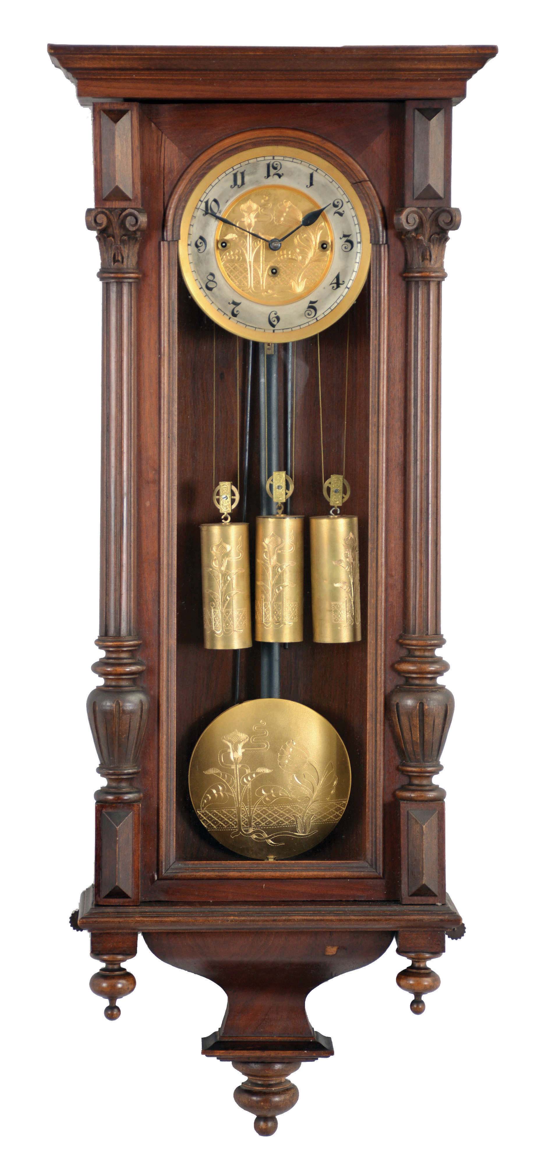 Clocks- 2 (Two): Both Vienna regulators, the first with veneered walnut case, ogee bottom bracket, door with applied half columns, arabic numeral silvered dial with sunk center, blued steel hands, and 8 day, quarter chiming, weight driven movement, the other with walnut veneered case, gadrooned bracket, door with applied half columns, and crest with carved and turned elements, Roman numeral white enamel dial, blued steel hands, and 8 day, time and strike, weight driven movement, dimensions of larger clock listed — Antique Clocks Price Guide
