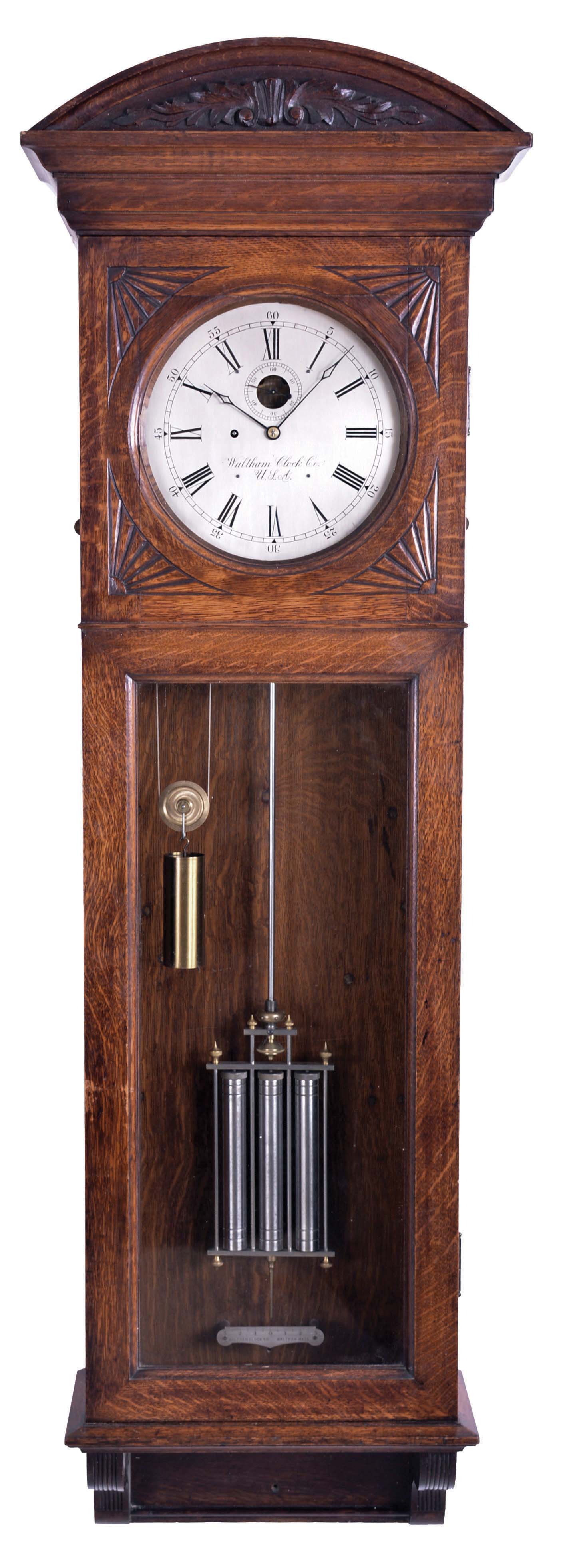 Waltham Clock Co., Waltham, Mass., "Regulator No. 14", jeweler's regulator wall clock, oak and quarter sawn oak case with fan carvings and carved arch top, Roman numeral silvered dial with blued steel hands, 8 day, ornately damascened weight driven timepiece movement with Graham dead beat escapement, and nickel plated three vial mercury pendulum with metal jars — Antique Clocks Price Guide
