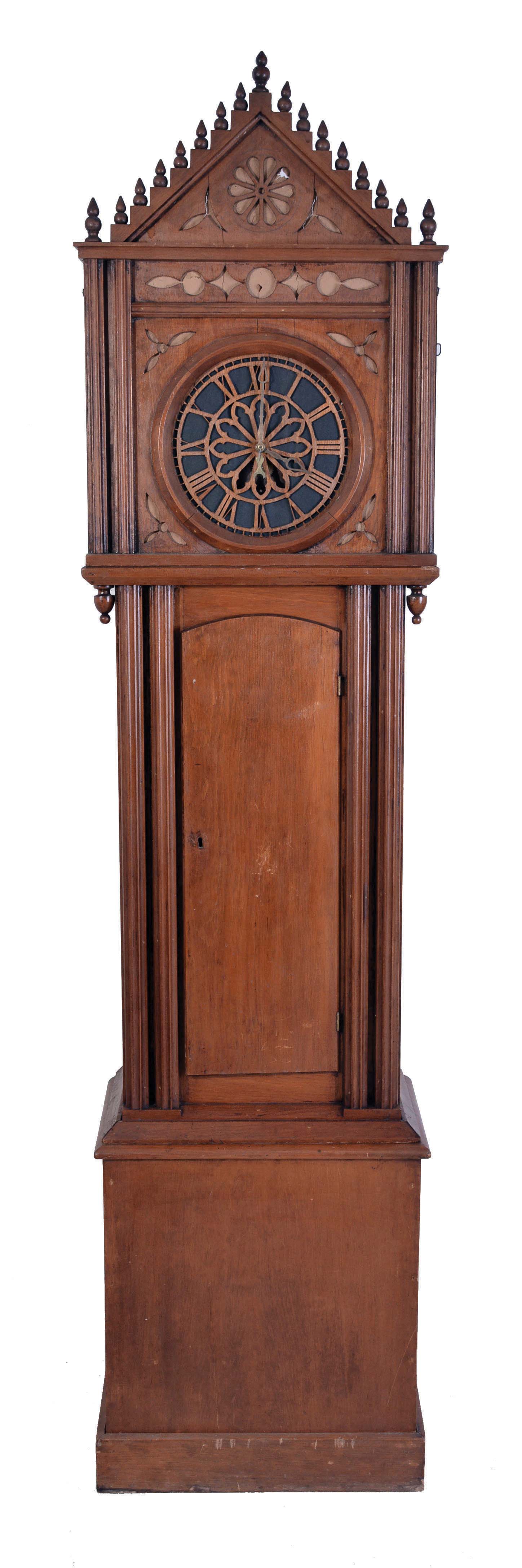 Germany, tall clock with 8 tune barrel organ, Gothic style softwood case, tall rectangular base below the trunk with fluted columns flanking the door, bonnet with decorative piercing, and stepped gable trim set with 15 turned finials, Roman numeral skeletonized dial with paper backing, brass, pierced spade hands, barrel organ playing eight tunes on twenty wooden pipes, cast iron weights, winding crank and brass pendulum ball — Antique Clocks Price Guide