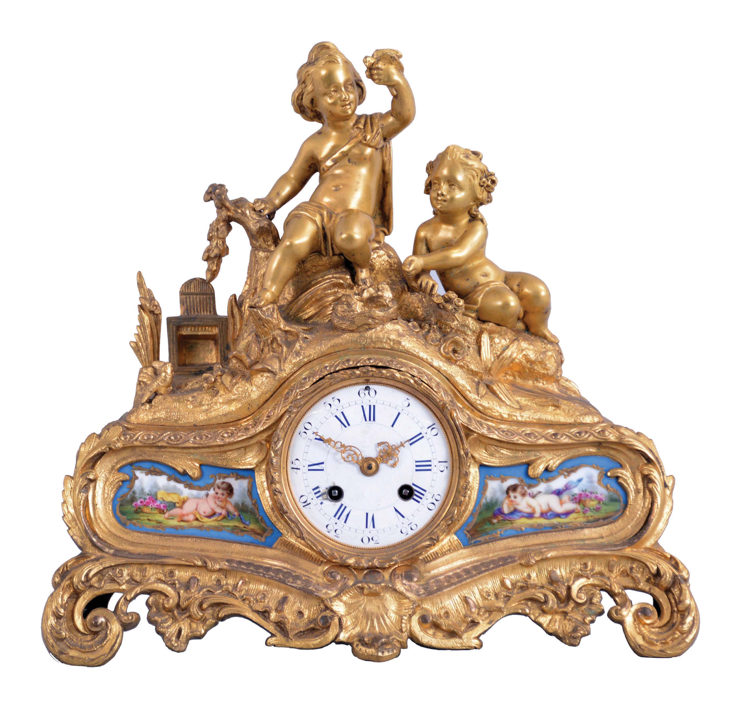 Rollin, a Paris, a gilt bronze mantel clock with porcelain plaques, the base with scroll feet, and richly ornamented in the rococo style, the front set with polychrome enamel porcelain plaques flanking the Roman numeral, white enamel dial, depicting reclining amorini with baskets of flowers, the top also with a pair of well modeled amorini, in a landscape, stealing young birds from a nest, and 8 day, time and strike, pendule de Paris movement — Antique Clocks Price Guide