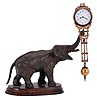 Junghans, Germany, elephant model swinging clock, patinated figure of an elephant mounted to a molded beechwood base, the 8 day swinging timepiece held aloft at the end of his trunk, clock case with gilt and silvered surfaces, Arabic numeral white enamel dial, blued steel hands, 8 day time only movement