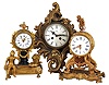 Clocks- 3 (Three) Gilt European: (1) France, figural mantel clock, 8 day time only balance wheel movement in a gilt cast brass and spelter case depicting a man with gardening implements and bagpipes with a white porcelain dial surrounded by laurels. (2) Mauthe Clock Company, Germany, miniature cartel clock, 8 day time and bim-bam bell strike in a gilt brass cartouche case. (3) France, mantel clock, 8 day time only balance wheel movement in a gilt cast brass and spelter case topped by Cupid with his bow with a white porcelain dial with Roman numerals.