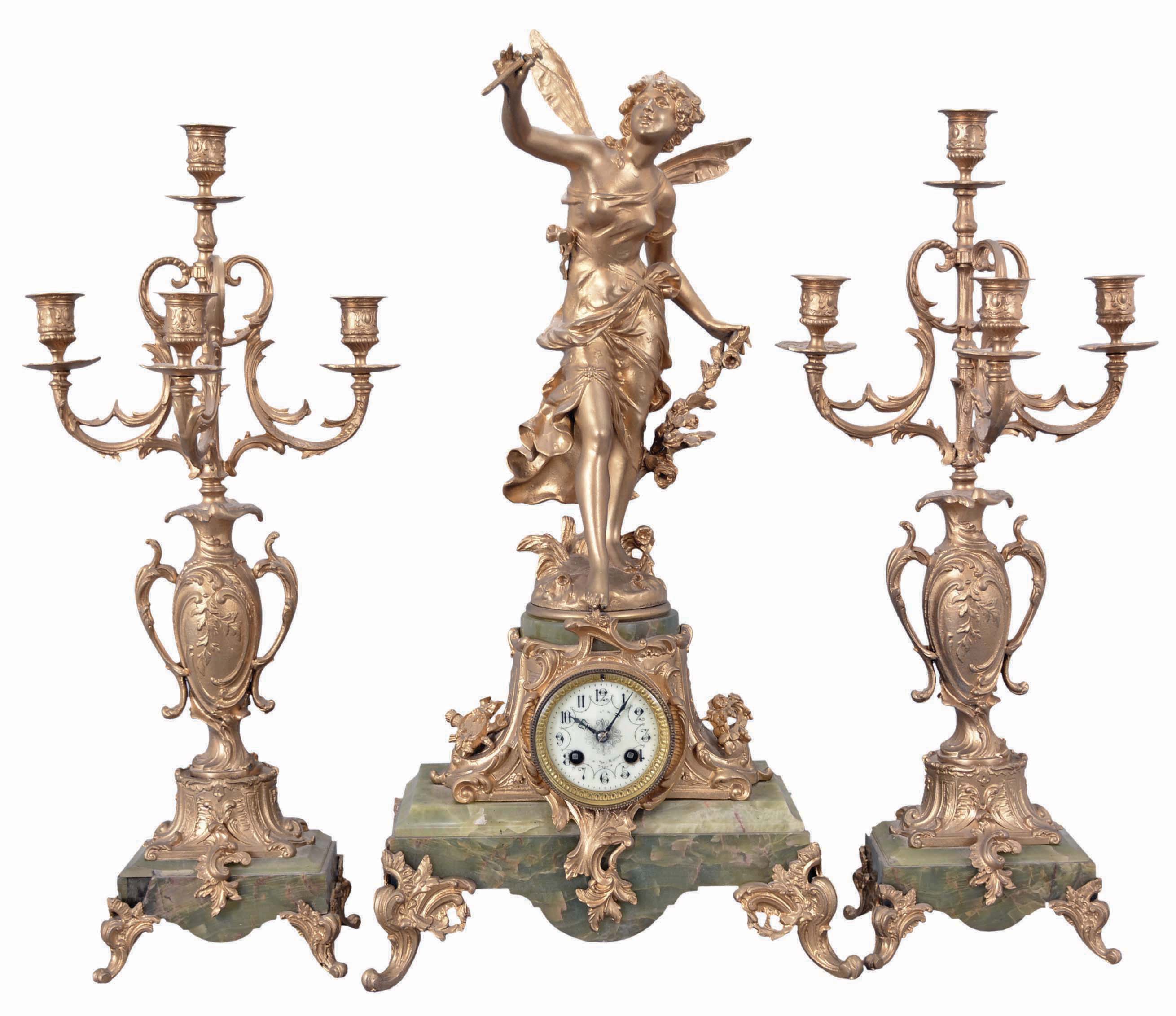 France, three-piece figural mantel clock with garniture, green onyx base on cast rococo feet supporting clock with porcelain dial set within an ornate tapered column, surmounted by a cast spelter female figure with delicate wings. The movement is an 8 day spring driven time and strike pendule de Paris signed by Marti &amp; Cie. Matching onyx and cast metal candelabra hold four candles each. — Antique Clocks Price Guide