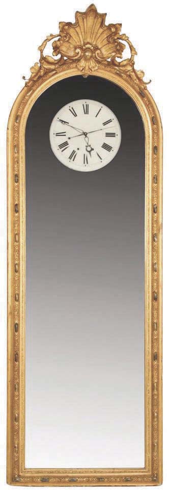 American or English, an unusual 30 day pier glass regulator with center seconds, the frame with gilt, repeating ornament and surmounted by gilt, sculptural foliate elements and central shell, the frame hinged to a pine case containing a large, 30 day weight driven timepiece movement with seconds pendulum, dead beat escapement, stop work, lantern pinions, and brass plates with turned iron pillars, mounted to a cast iron plate set into the case back, and white painted Roman numeral metal dial, with fancy, openwork blued steel moon hands, cast iron weights and wooden pendulum rod with heavy brass clad ball. — Antique Clocks Price Guide