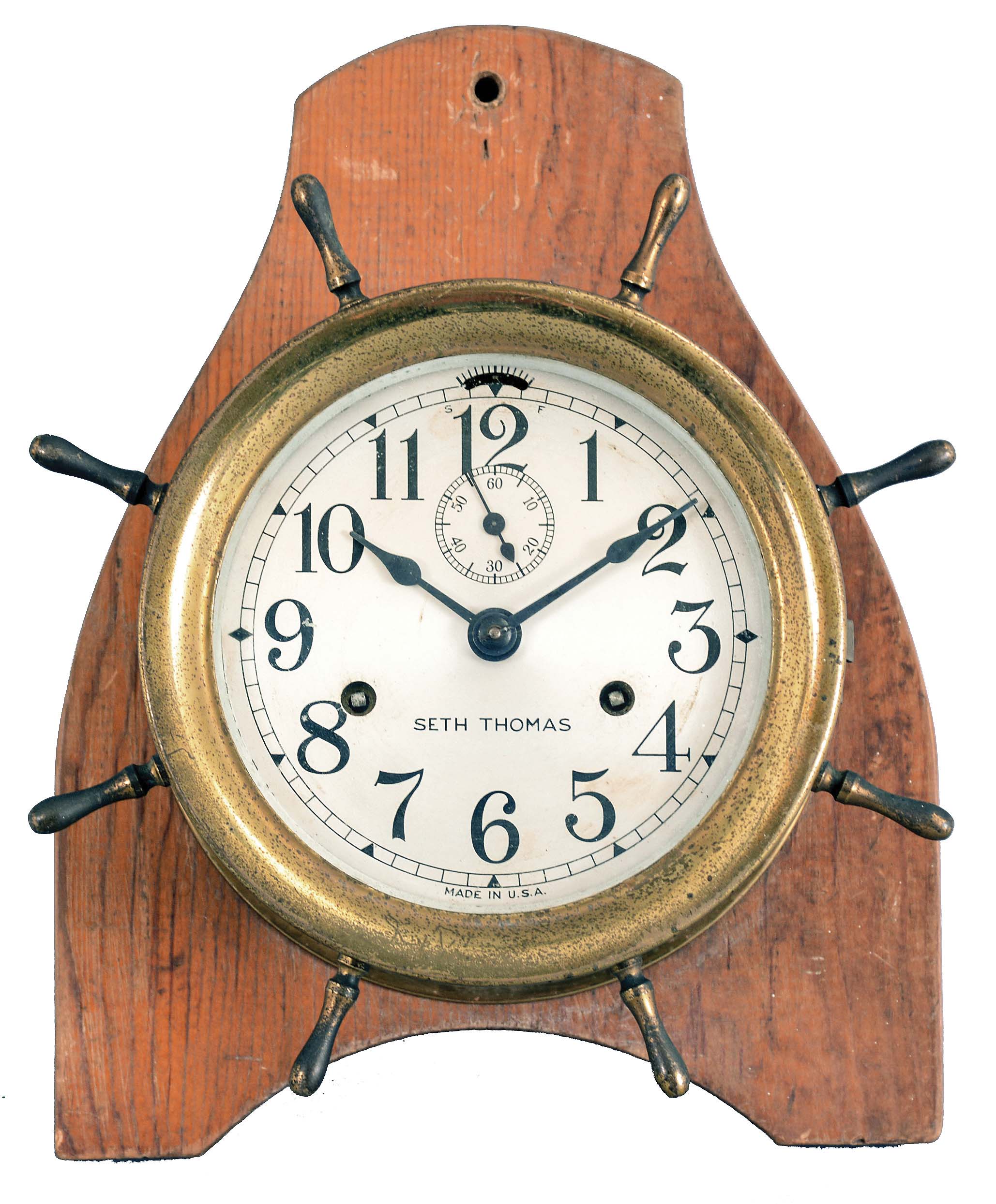Seth Thomas Clock Co., Thomaston, Conn., "Merrimac" ship's clock, 30 hour, time and ship's bell strike in brass case with radial handles resembling a ship's wheel mounted to pine board to facilitate wall hanging, 5 inch silvered dial. — Antique Clocks Price Guide