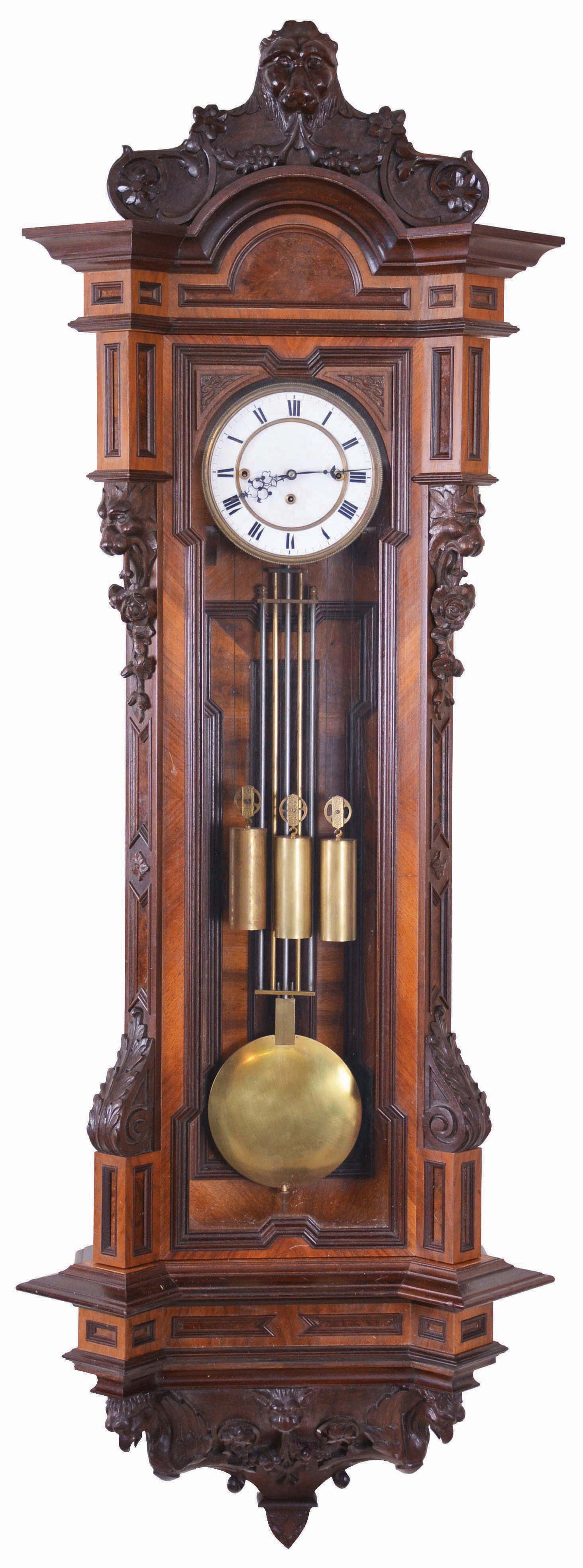 European, 3-weight "Vienna Regulator", grande sonnerie in a large 72 beat version, the modern walnut case carefully copied from an original, with canted corners, dozens of small frame moldings accenting burled insets, and carved with lions heads and roses at top, and acanthus leaves near bottom of door. The base itself fully carved with winged eagles and leafy scrolls. Removable top trim with large carved lions head and floral accents. — Antique Clocks Price Guide