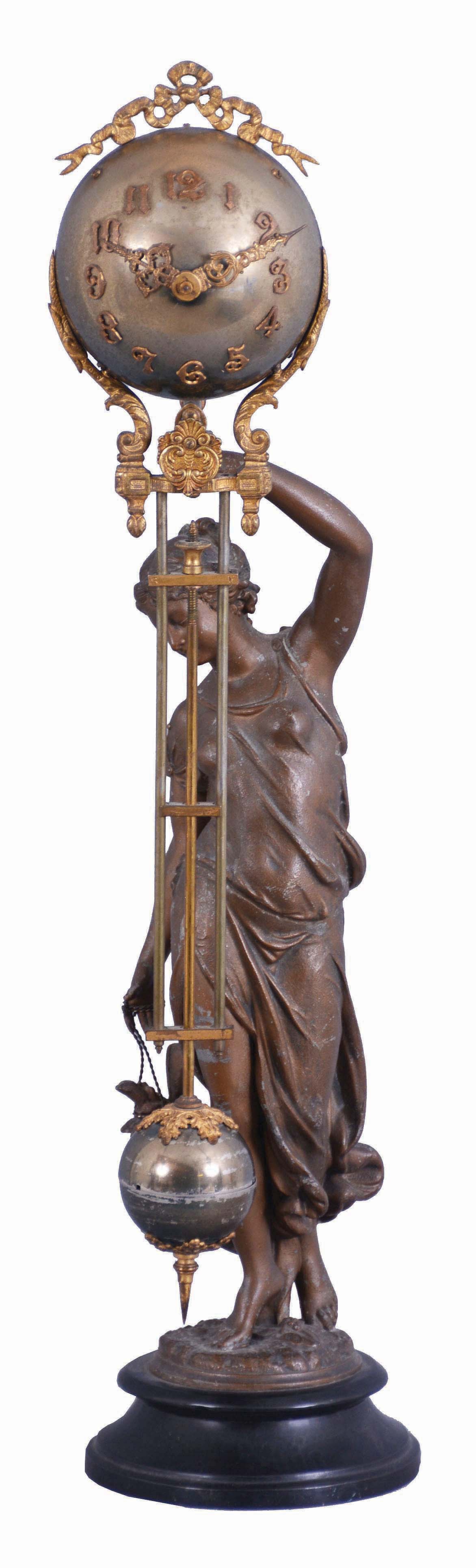 Ansonia Clock Co., New York, "Huntress" figural swinger, 8 day, time only, spring driven movement mounted inside a brass sphere with cast ribbon ornament and applied Arabic numerals, Louis XV style hands, the lower section in gridiron style with smaller sphere at the bottom, all supported by patinated spelter figure of a young woman carrying game birds standing atop an ebonized cast iron base, c1900. — Antique Clocks Price Guide