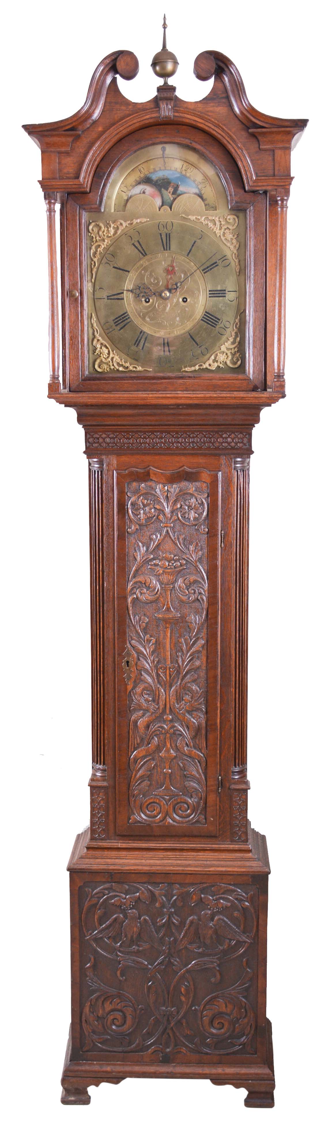 Benson, Whitehaven, England, tall case clock, 8 day, time and bell strike, weight driven movement in a carved oak case with broken arch top, center brass finial, full turned columns flanking hood resting on ogee feet. The engraved brass dial has applied spandrels and calendar off center — Antique Clocks Price Guide