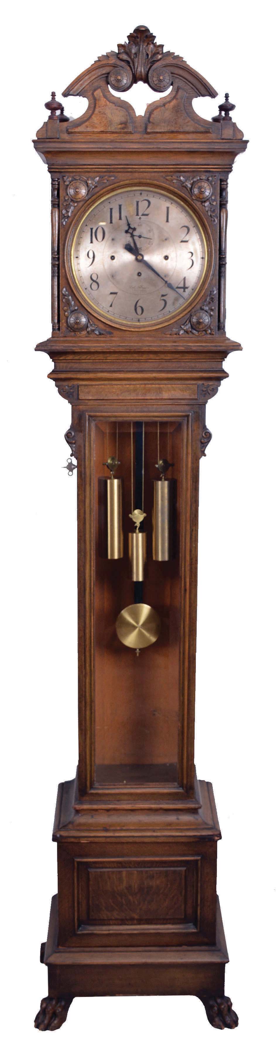 Seth Thomas Clock Co., Thomaston, Conn., "Regulator No. 21" later known as "Hall Clock No. 21" tall clock, 8 day, time, hour and Westminster chimes on a nest of 4 bells, weight driven movement with dead beat escapement in an oak case with beveled glass trunk door and carvings, paw feet and silvered brass dial — Antique Clocks Price Guide