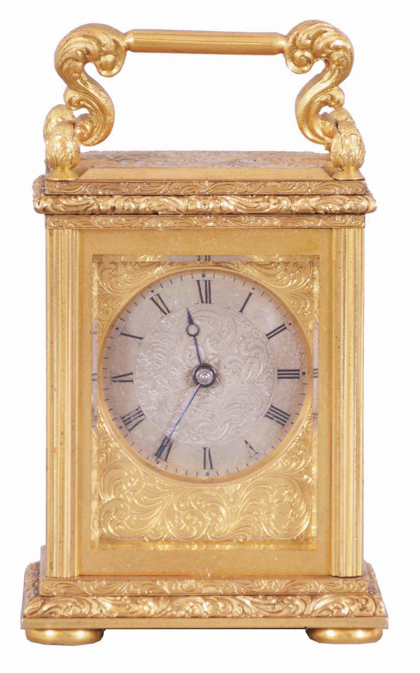 England, a very decorative miniature carriage timepiece, the gilt case with expertly engraved foliate ornament, the corners with reeded columns, surmounted by chased and engraved finials, the top with acanthus decorated handle, Roman numeral silvered dial with engraved center and gilt, engraved mask, blued steel Breguet style hands, 8 day timepiece movement with lever escapement, and spring barrel fixed to the front plate — Antique Clocks Price Guide