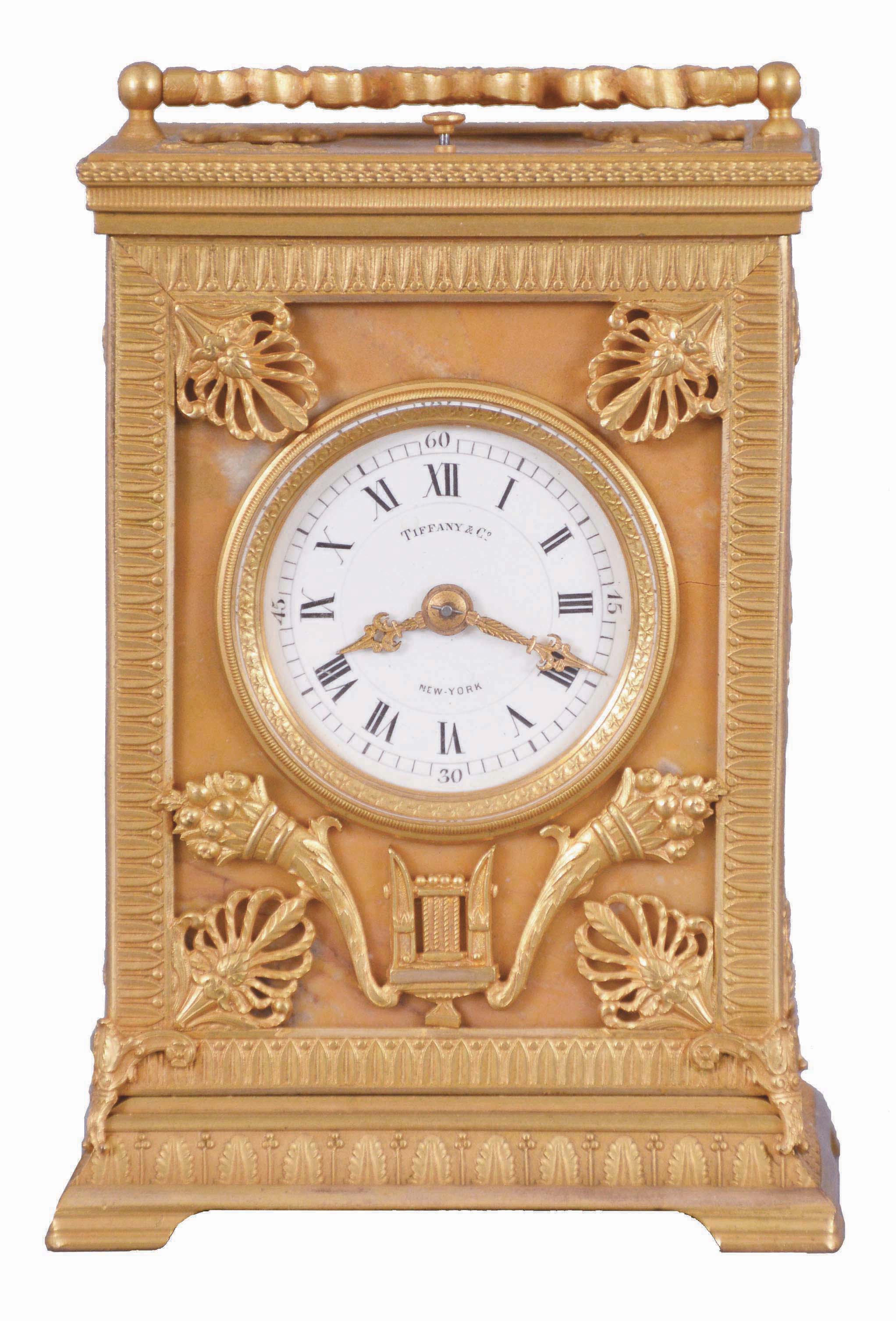 Ed. Chartier, Paris, for Tiffany &amp; Co., New York, a fine gilt bronze and sienna marble carriage clock in the neoclassical style, the case set with five stone panels, within leaf molded surrounds having anthemion corners, the front with Roman numeral white enamel dial and gilt hands, above horn of plenty and lyre ornament, the case sides set with a single, dancing muse, and the top with carrying handle of bowknot and trailing ribbon form, with central laurel wreath, 8 day time, strike, and alarm movement with lever platform, repeating the last hour on demand, serial #12837, case and movement signed by Chartier — Antique Clocks Price Guide