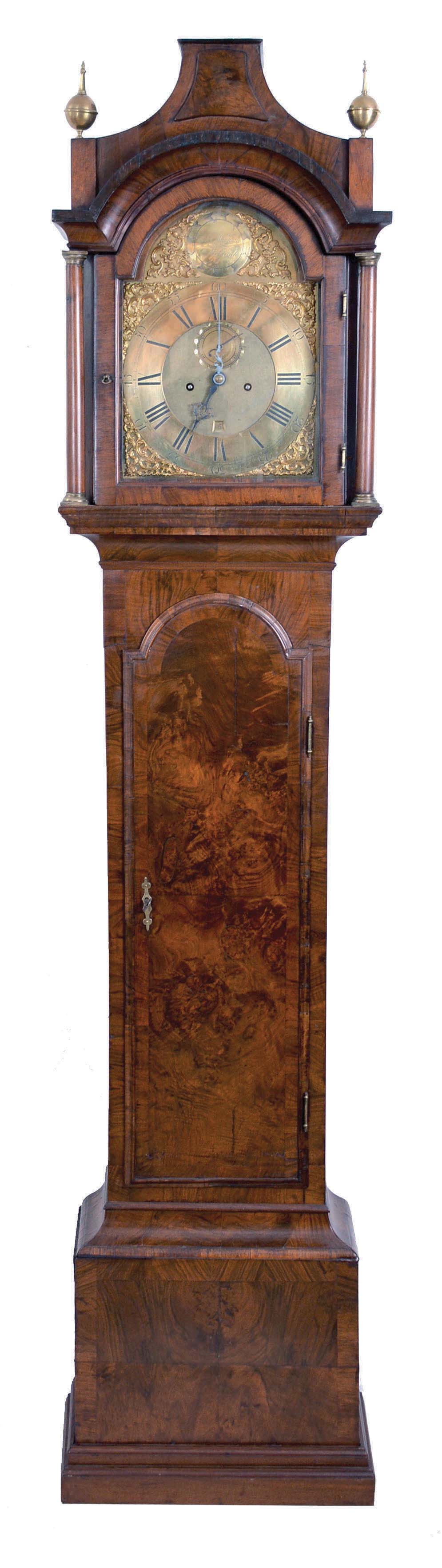 George Maynard, Melford, England, 8 day, time and strike, weight driven movement in a very handsome pagoda top burled walnut case, tombstone trunk door with cove molding. molded base, two full columns flanking hood door and spun brass finials. The brass dial has applied spandrels, maker's signature in boss surrounded by applied brass elements and calendar aperture at 6. — Antique Clocks Price Guide