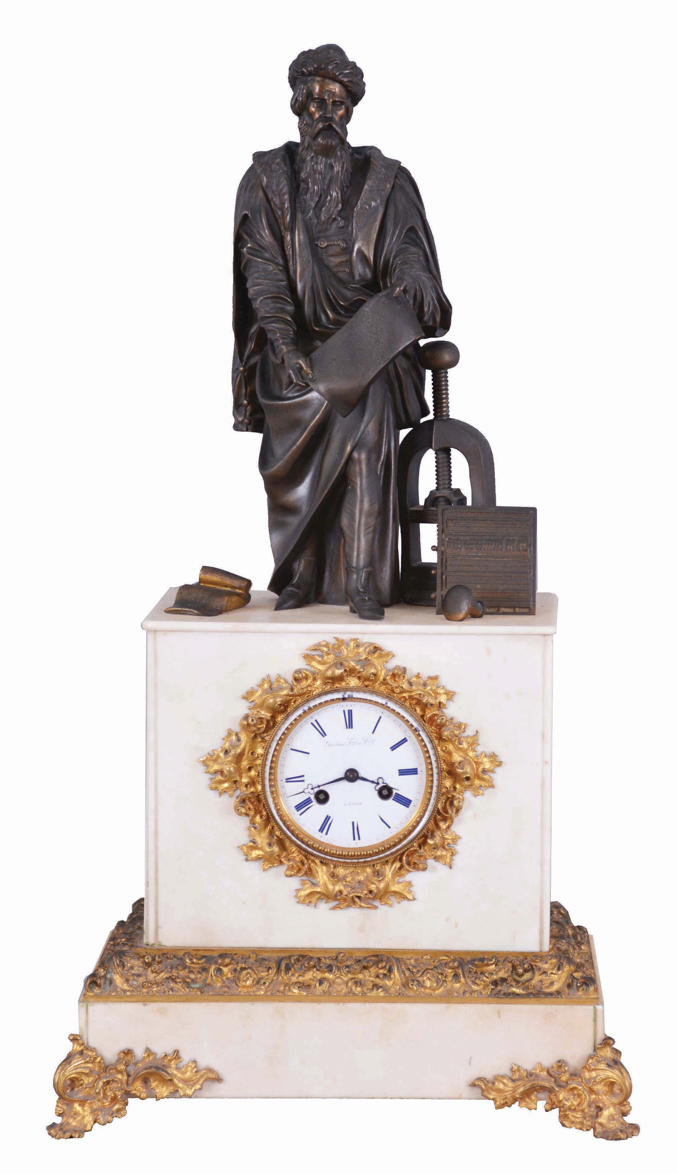 France, marble &amp; bronze, monumental figure clock of Johann Gutenberg (1399--1468), standing next to his printing press, and a large chase with a line of type. He is holding a page just printed showing the reverse of the type in the chase. To the right of his foot is an open book, with the title 'BIBLIA LATINA', and beyond his left foot the ink tool or spreader. And with a well made bell strike movement, silk thread suspension. fancy gilt bezel and glazed dial cover. The porcelain dial signed Gorini Freres &amp; Cie, a Paris. — Antique Clocks Price Guide