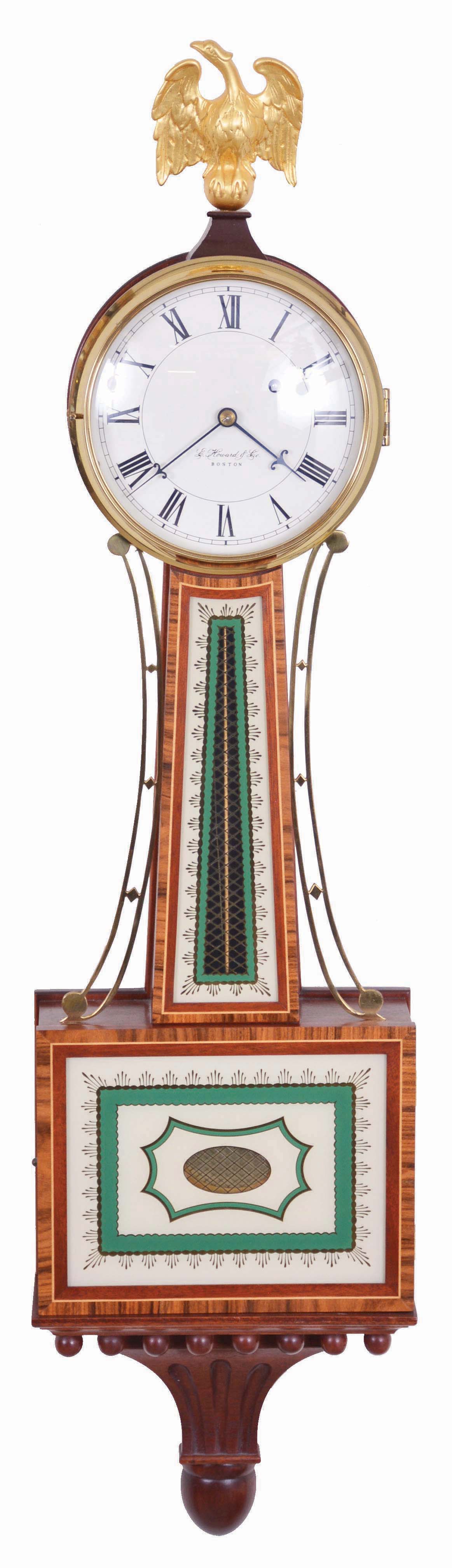E. Howard &amp; Co., Boston, Mass., "Model 95" Re-issue, Serial No. 124, gilt brass eagle surmounting the brass bezel which opens to the roman numeral dial marked "E. Howard &amp; Co./Boston", cross banded inlaid frames house the reverse-painted glasses of the geometric and cross hatched pattern in green, gold leaf and off-white, cast brass side ornaments flank the waist section and a carved pedestal completes the design at the bottom, eight day brass time only movement stamped "E. Howard &amp; Co./Boston/ 95" with recoil escapement, powered by a weight and regulated by a brass faced pendulum bob and brass rod. — Antique Clocks Price Guide