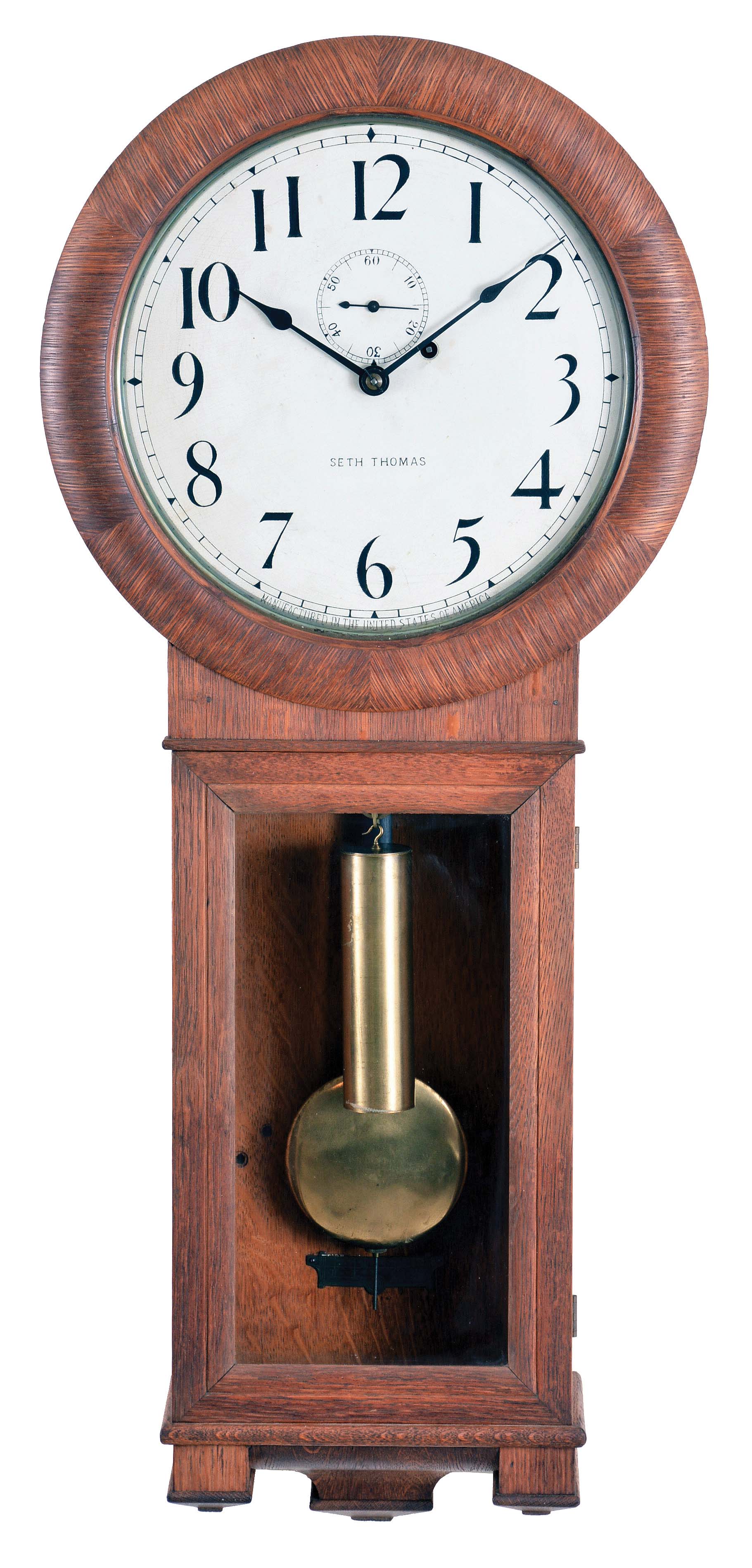 Seth Thomas Clock Co., Thomaston, Conn., "Regulator No. 2" wall clock, oak, with turned bezel over the painted zinc arabic numeral dial marked "Seth Thomas" and "Made in the United States of America", the lower glazed door unlocks with the winding key, pendulum, beat scale, cylindrical brass weight and remnants of original printed label in the base, eight day brass time only movement with dead beat escapement, maintaining power and lantern pinions all mounted to an iron frame attached to the backboard. — Antique Clocks Price Guide