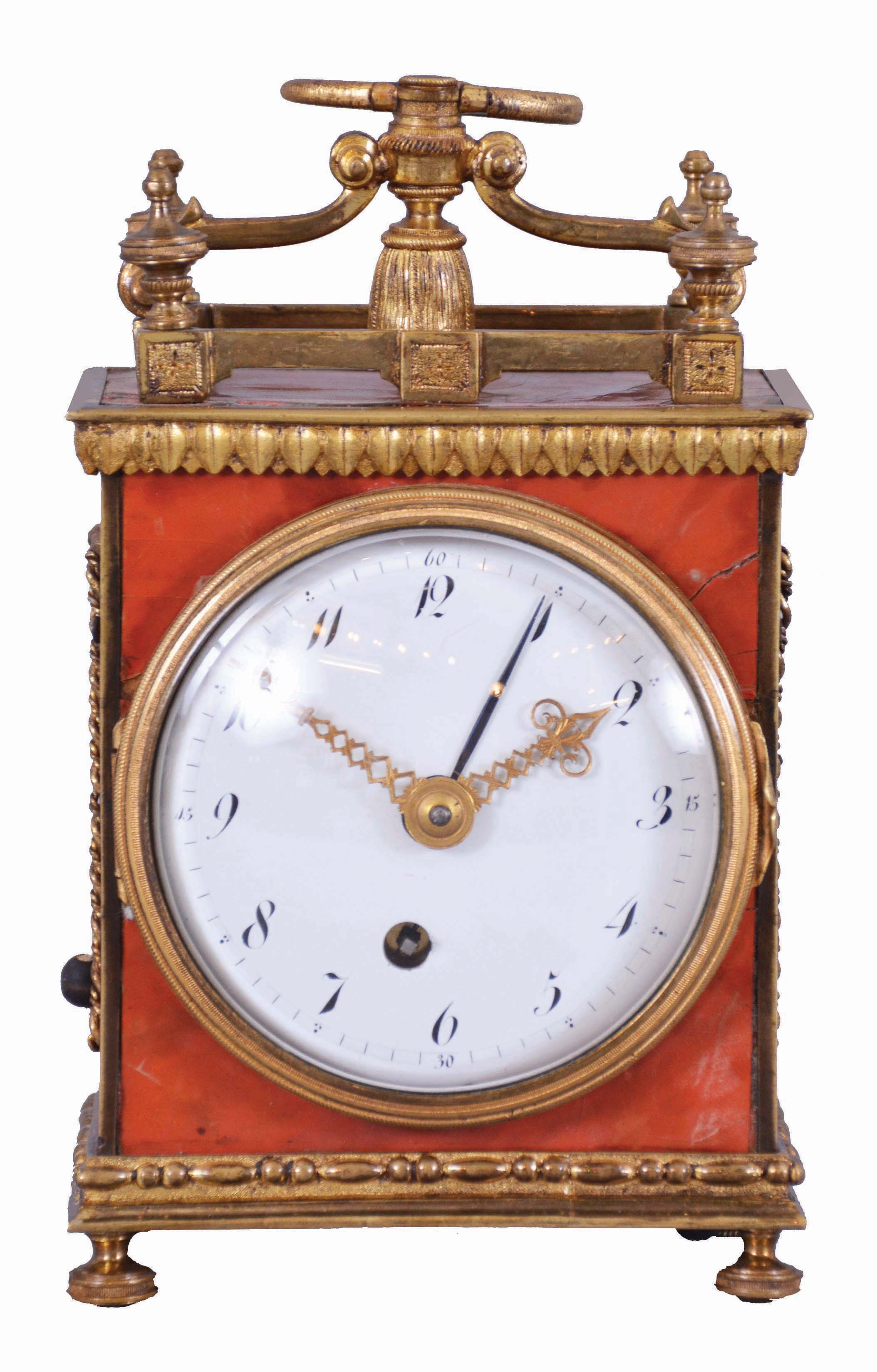 Switzerland, a Pendule d'Officer style travel clock, the dovetailed wooden case with underpainted horn veneer, gilt brass gallery with turned finials, cyma curved arms supporting a molded tassel below an Ouroboros form handle, gilt waterleaf cornice, gilt beaded and molded base on turned feet, and gilt rope molding framing lattice panels on sides and back, gilt bezel with convex glass, Arabic numeral white enamel dial, original pierced and engraved gilt hands, movement of two to three day duration, with Sully variant two plane escapement, with time, grand sonnerie strike on demand, and alarm functions, the strike and alarm trains wound by cords — Antique Clocks Price Guide