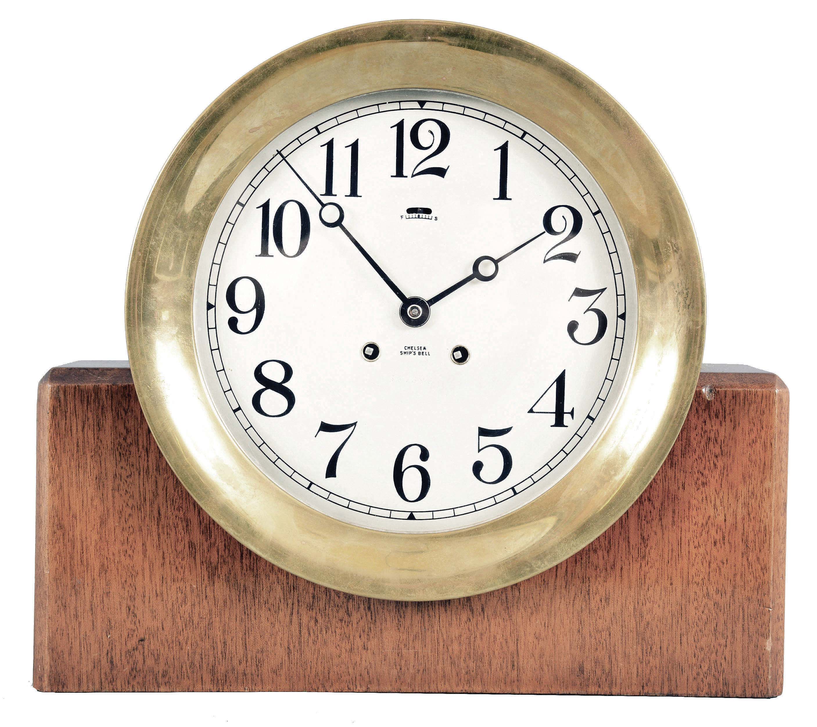 Chelsea Clock Co., Boston, Mass, "Mahogany and Metal" ship's clock, 8 day, time and ship's bells, spring driven jeweled movement in a heavy cast brass case with hinged bezel, 8 inch signed silvered dial, all on a rectangular mahogany stand. Serial number 527160. — Antique Clocks Price Guide