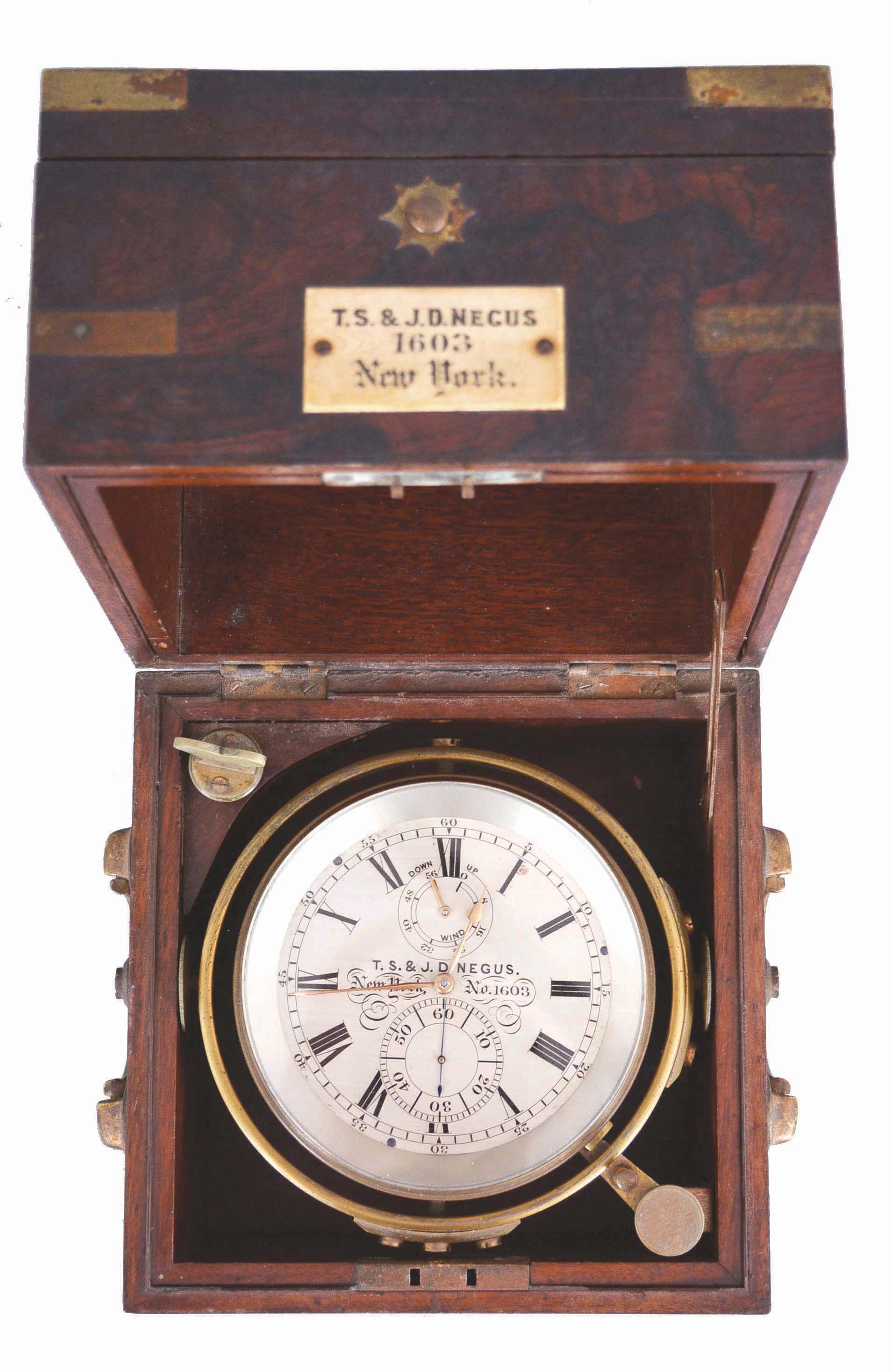 T.S. and J.D. Negus, New York, a good two day marine chronometer with original box, 11 jewel, free sprung fusee movement with Earnshaw's spring detent, cut, bimetallic chronometer balance with blued helical spring, and diamond endstone, signed Roman numeral silvered dial with wind indicator, gold spade and poker hands, contained in a lacquered brass bowl with gimbals, and mounted in a mahogany and rosewood veneer box with brass furniture, and plaque engraved "T.S. &amp; J.D. Negus 1603 New York", the box also with rating certificate from L. A. Karcher &amp; Co., Boston — Antique Clocks Price Guide