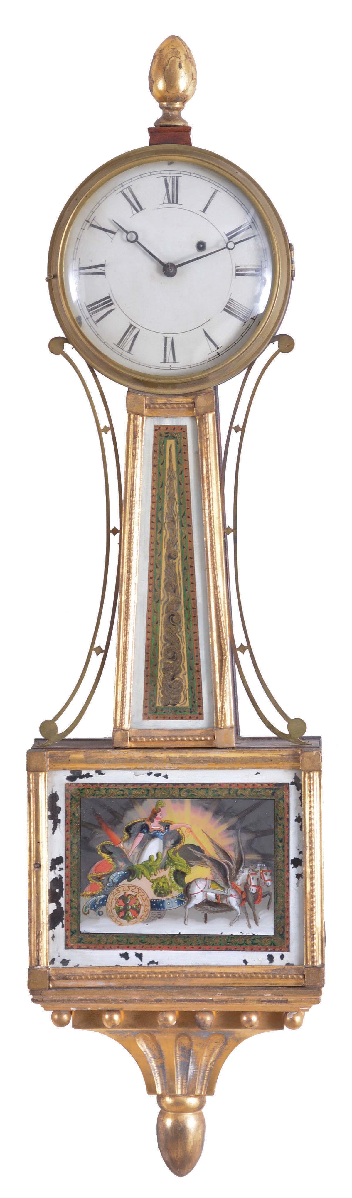 Patent Timepiece or "Banjo" Clock, Concord, Massachusetts, the mahogany veneered, gilded rope molded case with acorn finial over the zinc roman numeral dial, original reverse-painted glasses, the lower depicting "Aurora" on her festooned chariot driven by two winged horses set before a gleaming sunrise and framed within a geometric border, the waist glass flanked by brass side ornaments in gold, green and red frames gilt scroll work within a gilt border, below is a gilded pedestal with fluted acorn drop and eight balls, eight day brass movement with alternate train layout, cut-outs on front and back plates, and recoil escapement and regulated by a brass-faced lead backed pendulum bob and iron rod. — Antique Clocks Price Guide