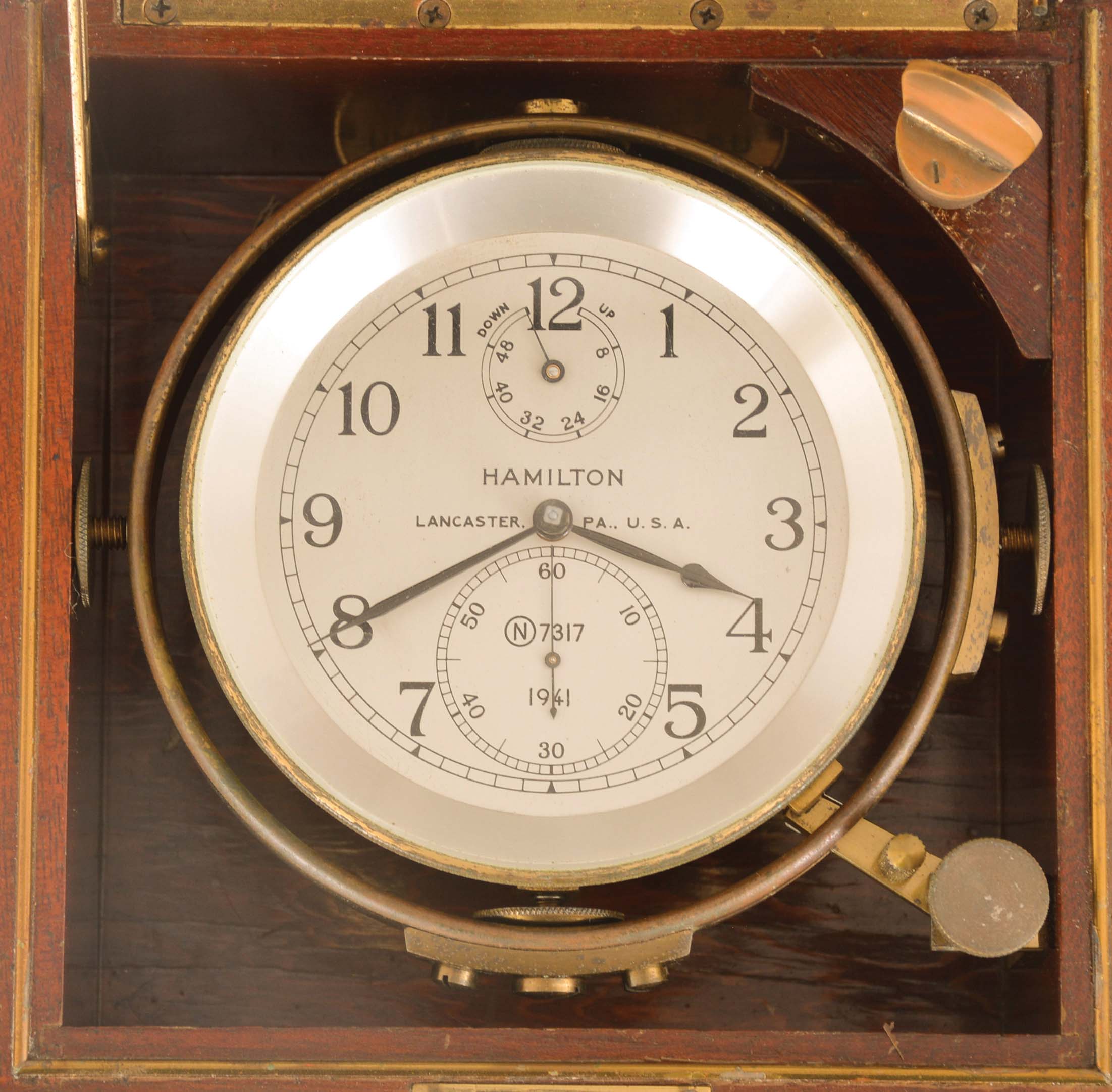 Hamilton Watch Co., Lancaster, Penn., model 21 marine chronometer, 14 jewel key wind and set, straight line damascened nickel plate movement, with spring detent escapement and chronometer balance with helical hairspring, Arabic numeral metal dial with wind indicator, black painted steel spade and poker hands, contained in a gimbaled brass bowl, and mounted in a mahogany box with brass hardware, the inside of the box top with instruction label, and contained in a larger, cherry outer box, serial #2E7317, c1940 — Antique Clocks Price Guide