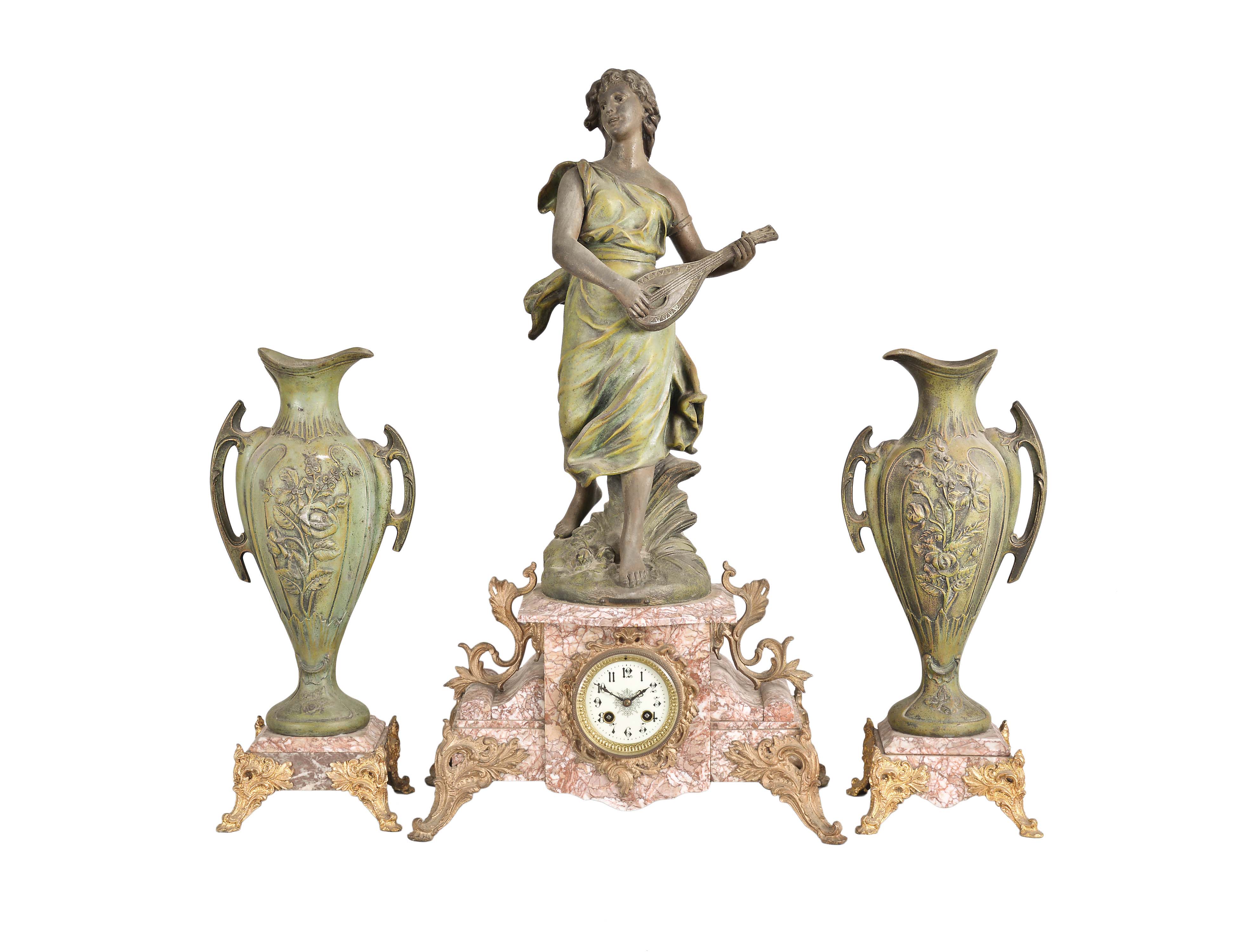 France, Variegated Pink Marble Figural Clock Garniture, the clock with off-white arabic numeral dial within a brass bezel and beveled glass set within the marble case with scroll work dial surround, on raised feet and and plinth for the statue titled "La Cigale" a sculpture first presented by Sylvain Kinsburger, the patinated figure of a young maiden no doubt playing the 'Song of the Cicada' on her lute, eight-day spring powered, round French movement with count-wheel hour and half hour strike on a bell, together with two matching and imposing ewers with floral facades and carrying handles on raised pink marble bases with gilt feet. — Antique Clocks Price Guide