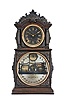 Ithaca Clock Co., Ithaca, New York, "3 1/2 Parlor" Calendar Clock with black and silvered roman numeral dial, tri-foil hands, lower clear glass reveals the glass calendar dial marked "H. B. Horton's Patents...Ithaca Calendar Clock Co./Ithaca, N.Y." with the perimeter in arabic numerals for the day of the month, black rolls with silver days and months set behind with calendar mechanism, eight day time and strike E. N, Welch movement striking on a silvered bell mounted below the movement, walnut case with ebonized composite carving on crest and spandrels, full free-standing columns flank the time dial and bezel, all on a two-stage molded base.