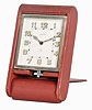 Cartier Folding Travel Clock in red leather case with dial signed "Cartier", "Swiss" and "8", radium Arabic numeral dial, radium hour and minute hands, eight-day time and alarm movement with pointer alarm hand set in a nickel case with lower winding/setting stem.