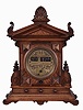 German "Digital Time" with fancy brass dial, in an architectural walnut case, brass pendulum regulated movement, has solid plates and open spring, running one day, gilt /tan numerals on paper rollers indicate the time, the right two rollers bearing the minutes, and rolling up similar to American calendar roller [or slot machine roller], springing quickly into next position. At the end of minute 59, the hour roller rotates, and the minutes are back to "00".