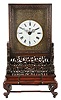 China, a carved camphorwood bracket clock with rotating stand, with pierced and glazed sides, front panel with foliate carving, base with pierced and carved fretwork, Roman numeral white enamel dial with engraved brass surround, blued steel hands, 8 day, time and strike fusee movement with verge escapement, and striking petit sonnerie quarters on two bells