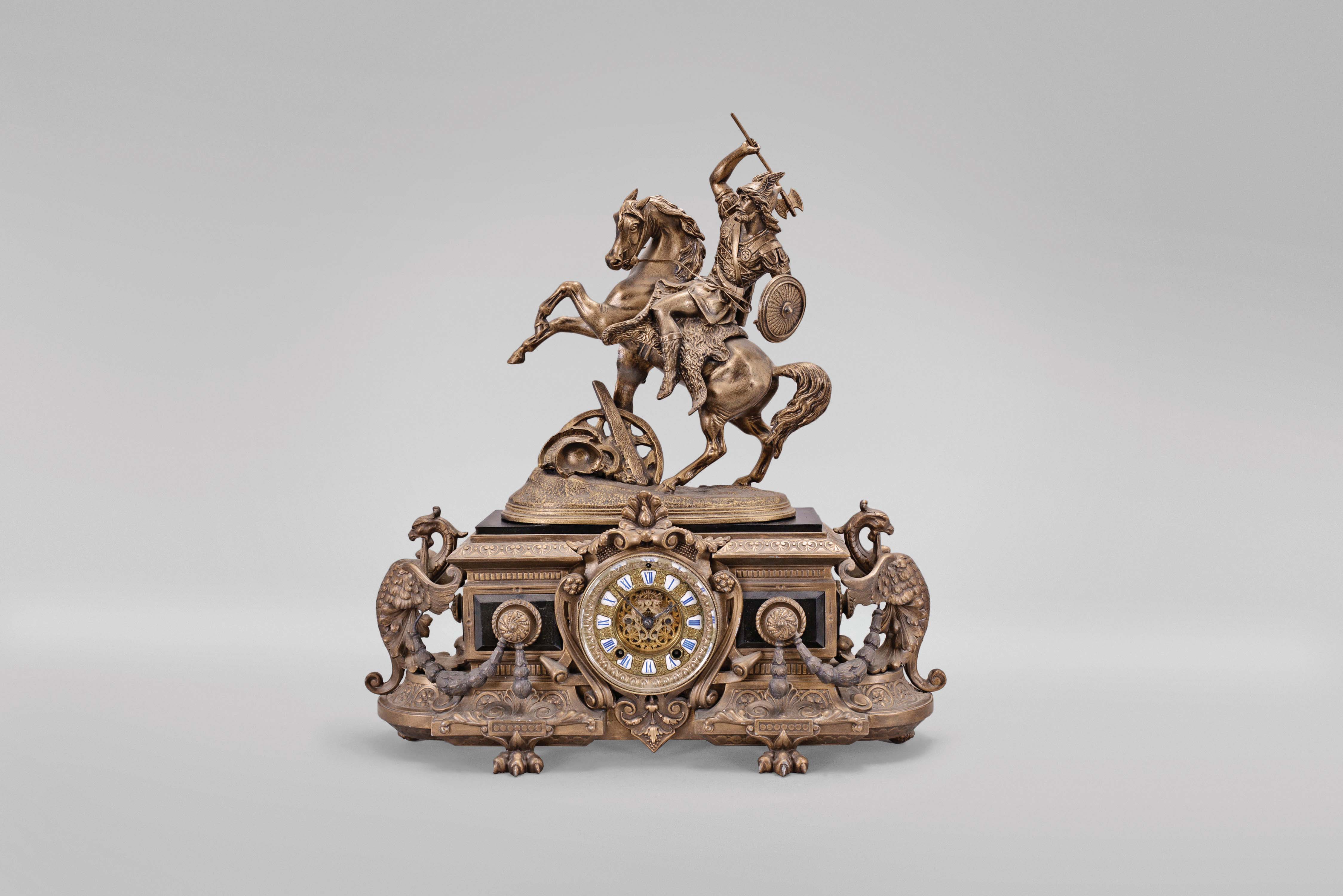 Ansonia Clock Co., New York, "Eureka (base) with Group No. 1099 (figure) " mantel clock with a spring driven, 8 day, time and half hour strike visible escapement movement in a bronze finished spelter and black enameled iron case. — Antique Clocks Price Guide