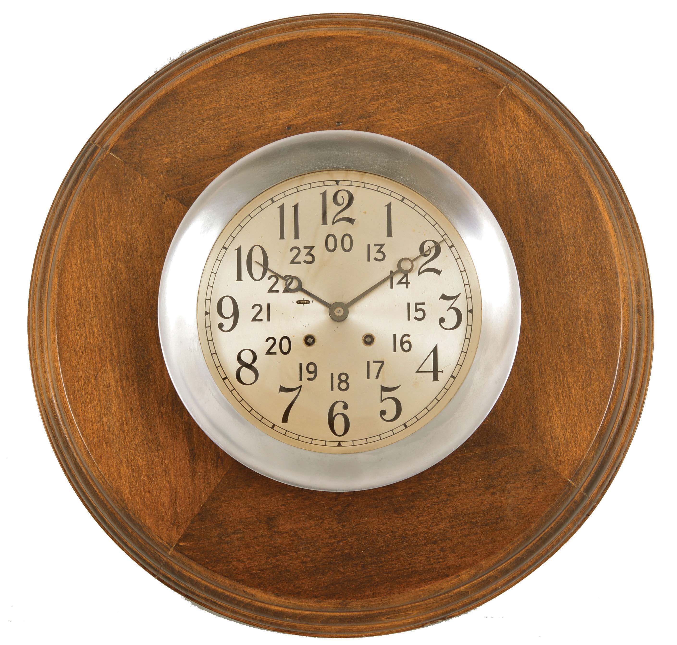 Chelsea Clock Co., Boston, Mass., wardroom clock, 8 day, time and ship's bells, spring-driven, balance wheel movement in a half-flush aluminum case with hinged bezel, partially recessed within a circular wooden wall mount, 7.5 inch silvered dial with inner ring showing 24 hour time, recessed electrical terminals to connect amplification for internal bell, movement serial number 559141. — Antique Clocks Price Guide