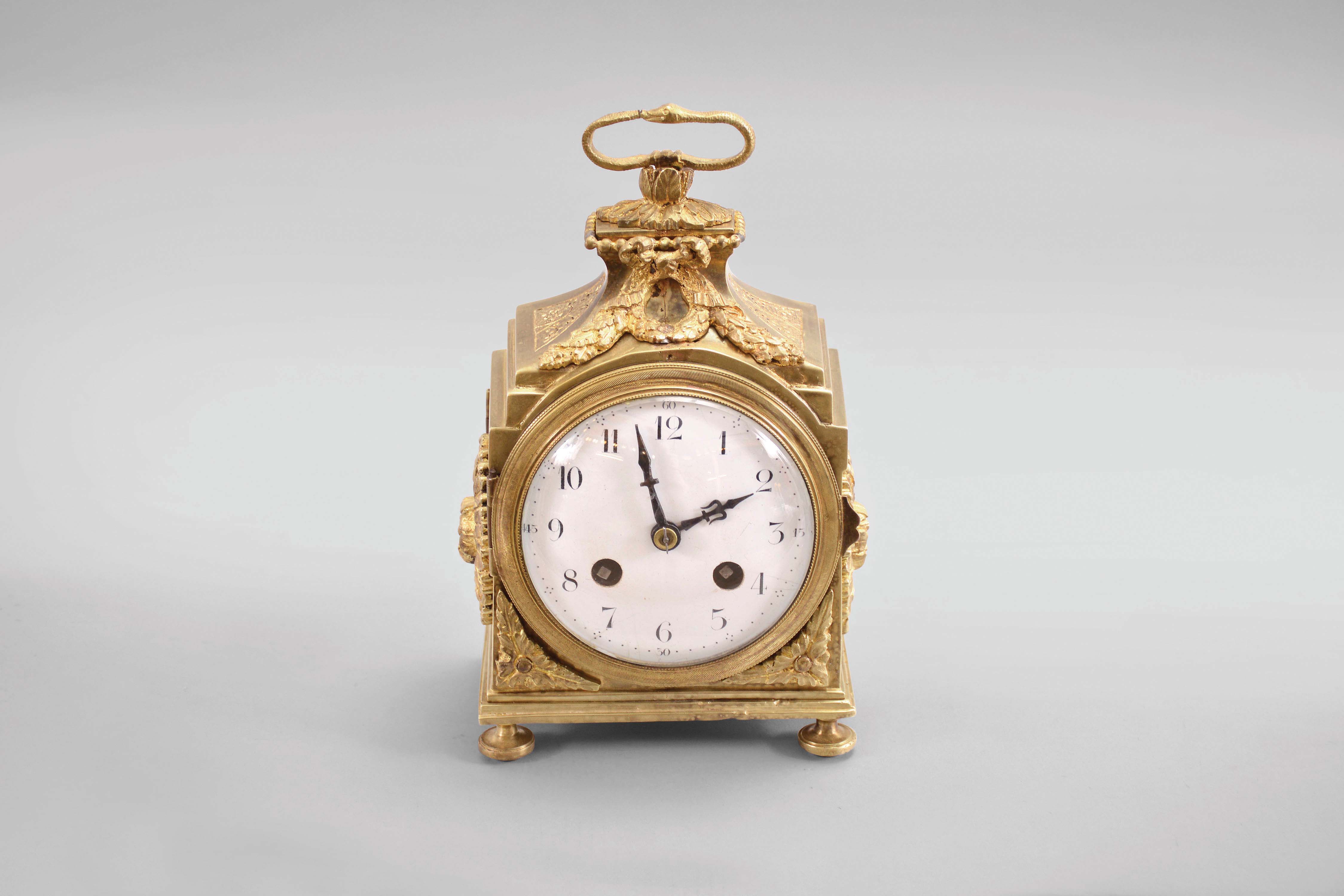 France, a late 19th century Pendule d'Officier style table clock, gilt brass case with applied foliate ornament and with ouroboros handle, arabic numeral white enamel dial, blued steel hands, 8 day, two train movement with lever platform — Antique Clocks Price Guide