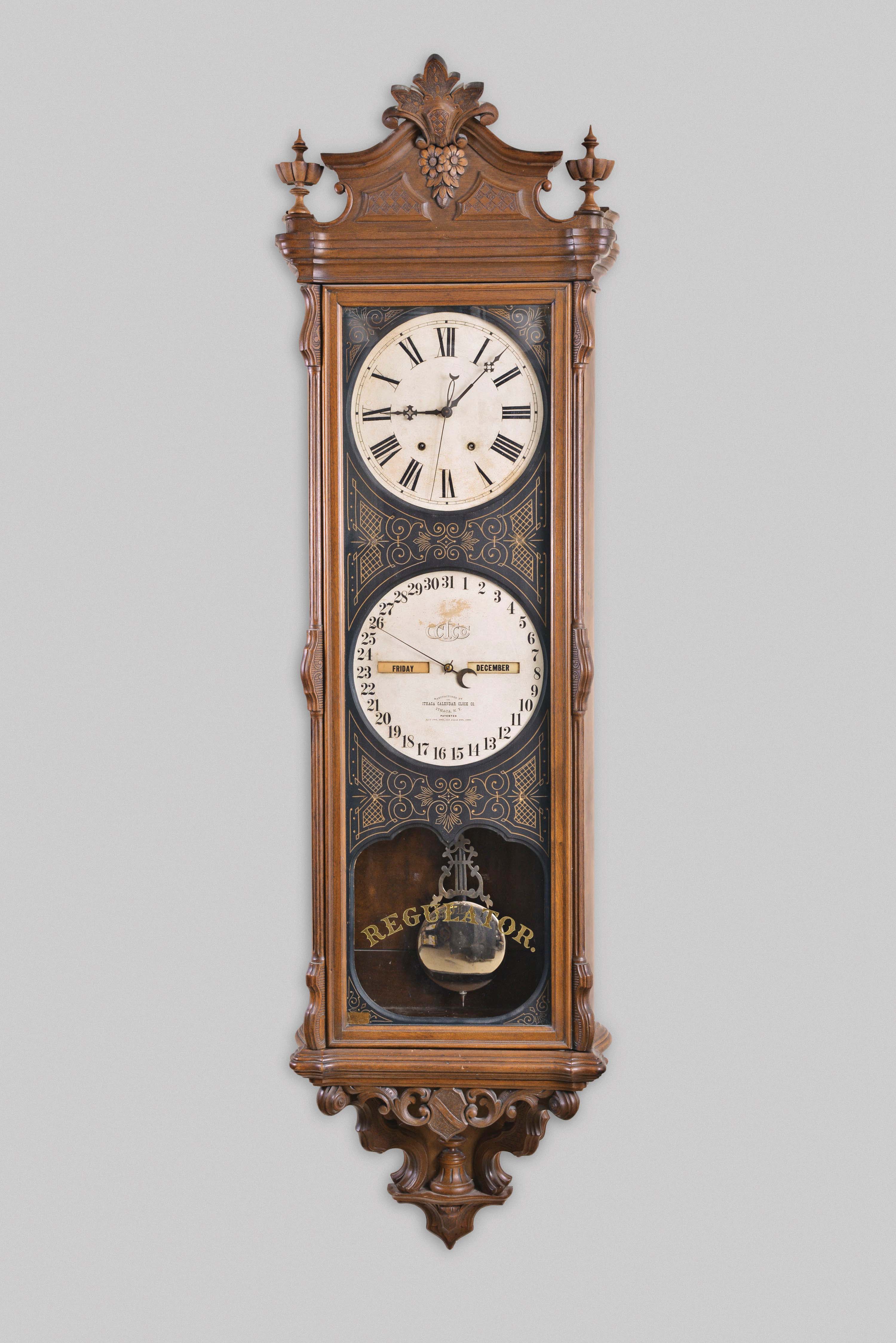 Ithaca Calendar Clock Co., Ithaca, N.Y., "No. 1 Regulator Sweep", hanging jeweler's regulator, 8 day, time with sweep seconds, perpetual calendar, double weight driven movement with a gridiron pendulum in a walnut case with carved crest and bottom with papered metal dials — Antique Clocks Price Guide