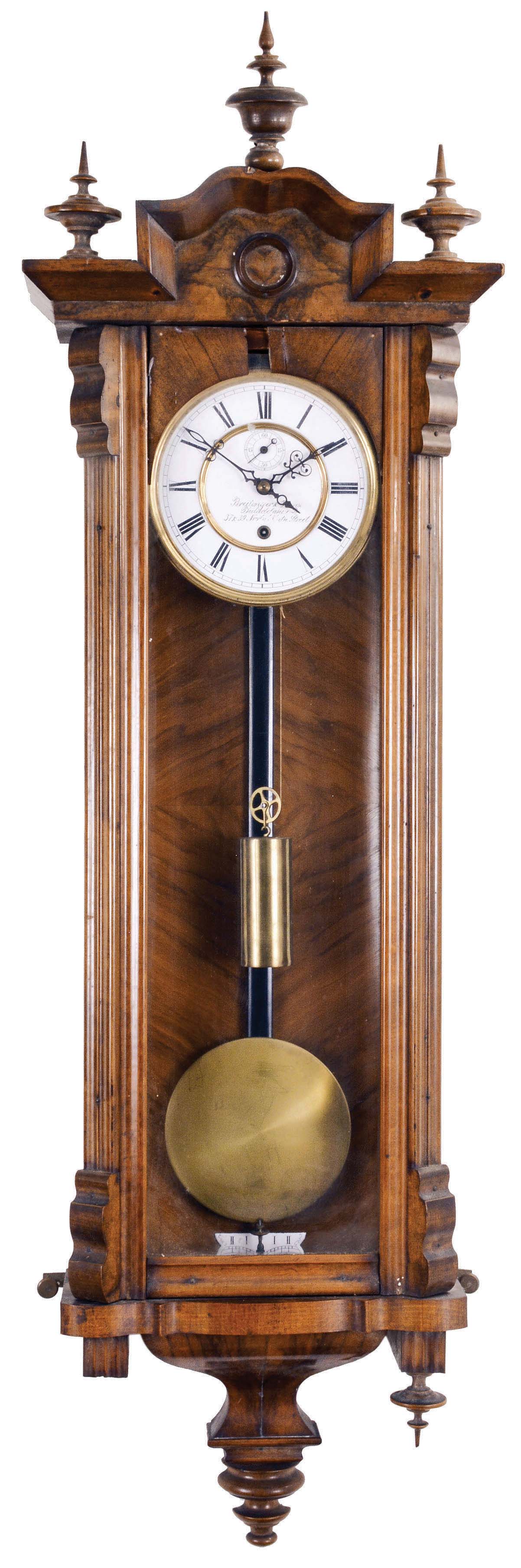 Gustav Becker, Freiberg, Germany, Vienna style regulator, 8 day, time only, weight driven movement in a walnut case with fluted columns flanking the door glass and turned ornaments, brass clad pendulum, white enamel dial reading in part "Breitinger &amp; Kunz / Philadelphia", subsidiary seconds, and blued steel hands. — Antique Clocks Price Guide